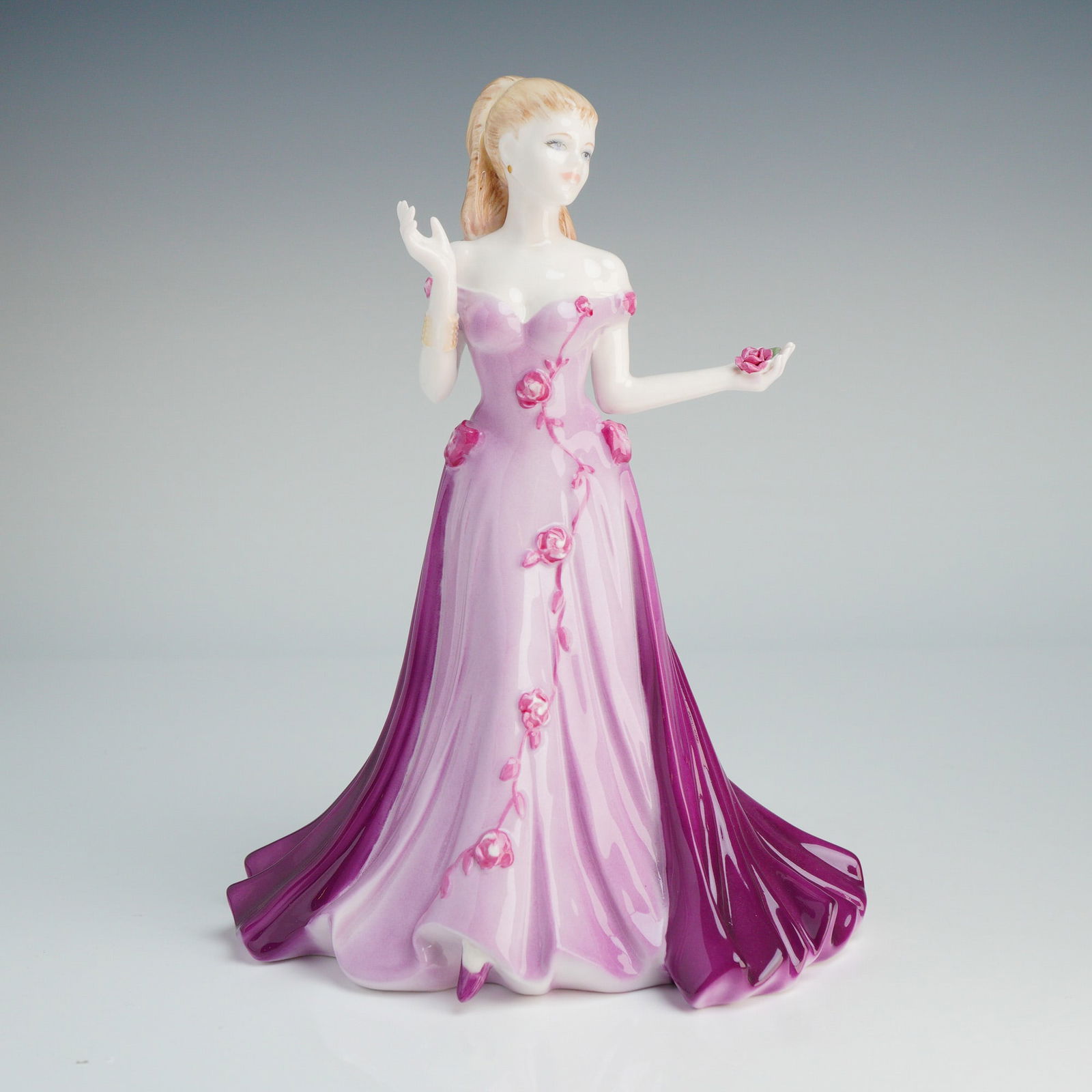 Coalport The Collingwood Collection Figurine, Barbara: This hand-decorated figure depicts a woman with blonde hair in an off-the-shoulder evening gown featuring lilac and plum tones, accented with small pink rosebuds trailing down the skirt. The figure is
