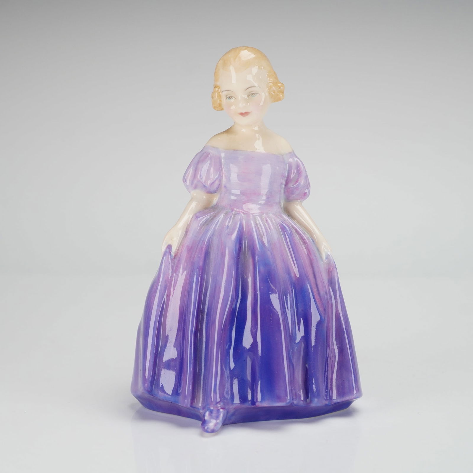 Royal Doulton Bone China Figurine, Marie HN1370: A hand-painted figure designed by Leslie Harradine for the Harradine "Child Classics" series, depicting a young girl with light-colored hair wearing a flowing gown in varying shades of purple, with th