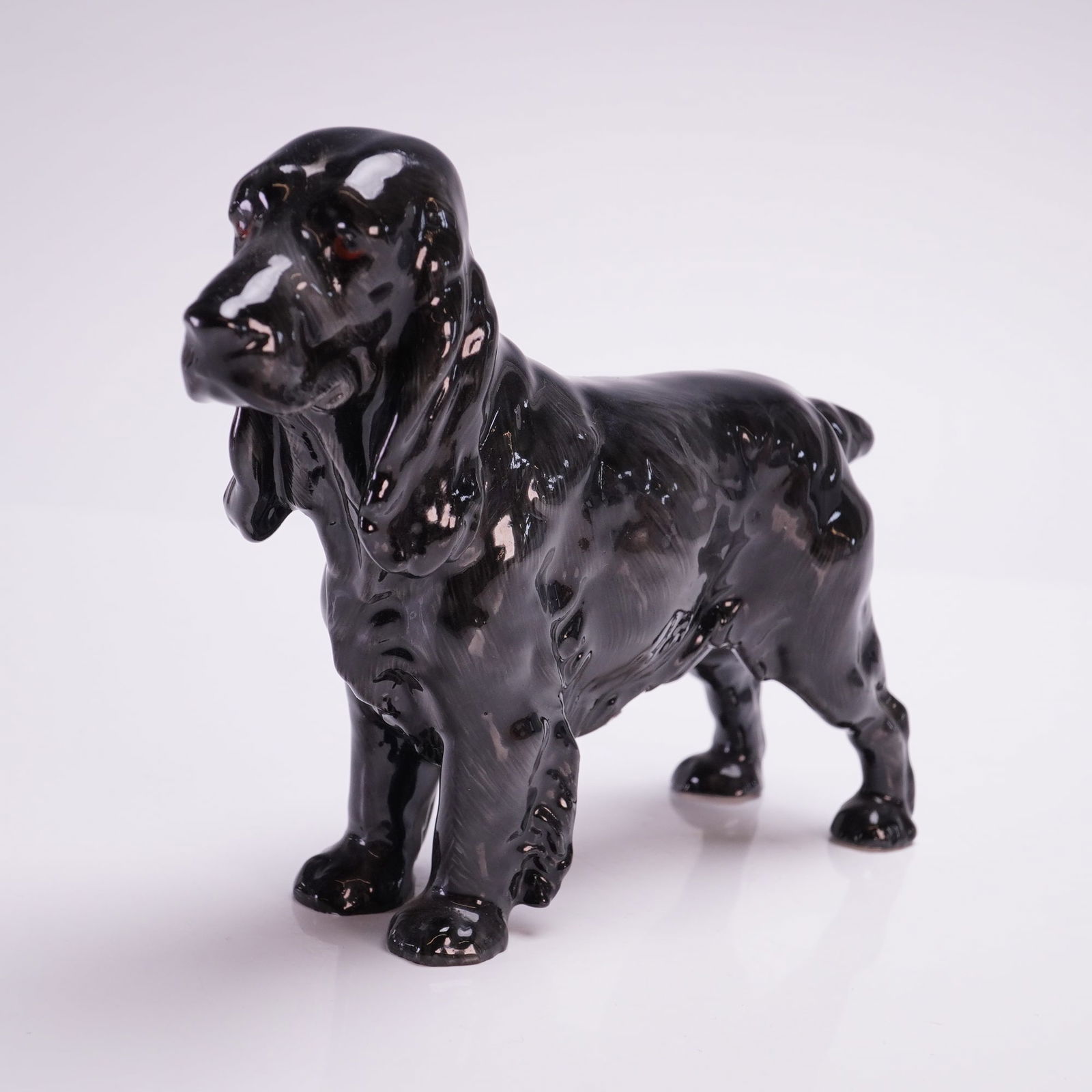 Royal Doulton Dog Figurine, Black Cocker Spaniel HN1020: The piece is finished in a high-gloss black glaze and features detailed modeling of the breed's characteristic long ears and textured coat. The underside of one paw bears a circular green manufacturer
