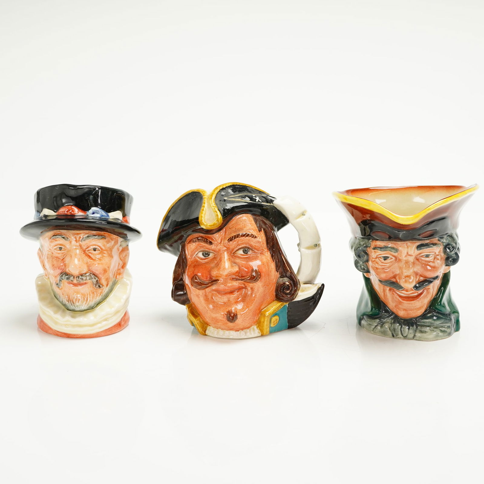 3pc Royal Doulton Small Character Jugs: A trio of Royal Doulton small Character Jugs, polychrome glazed ceramic, featuring highly detailed, hand-painted decoration and a high-gloss finish. The collection includes three distinct male charact