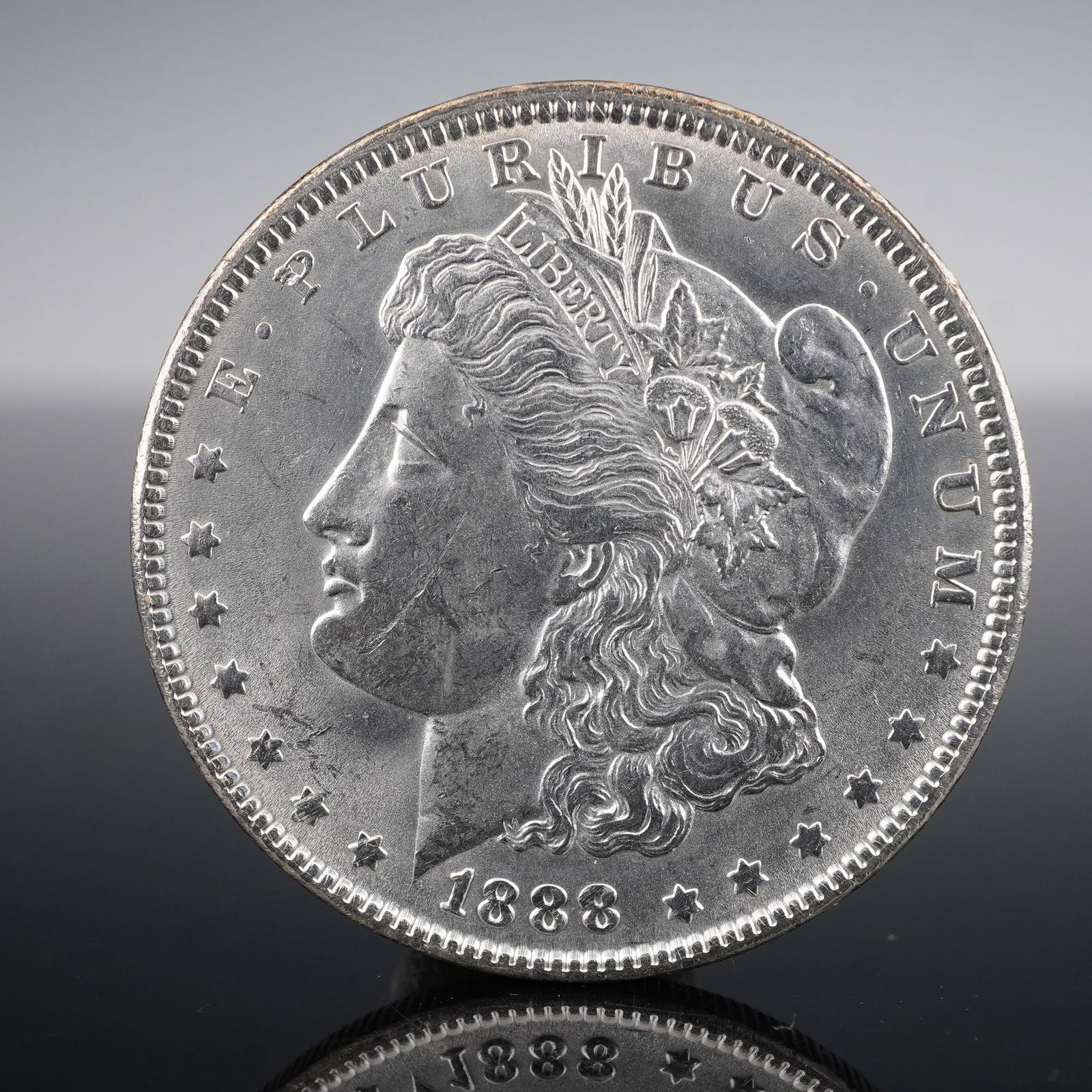 1888 Morgan Silver Dollar: Minted in 1888, this Morgan Silver Dollar was struck in the classic alloy of 90% silver. The obverse features George T. Morgan's neoclassical portrait of Liberty, adorned with a Phrygian cap and agric