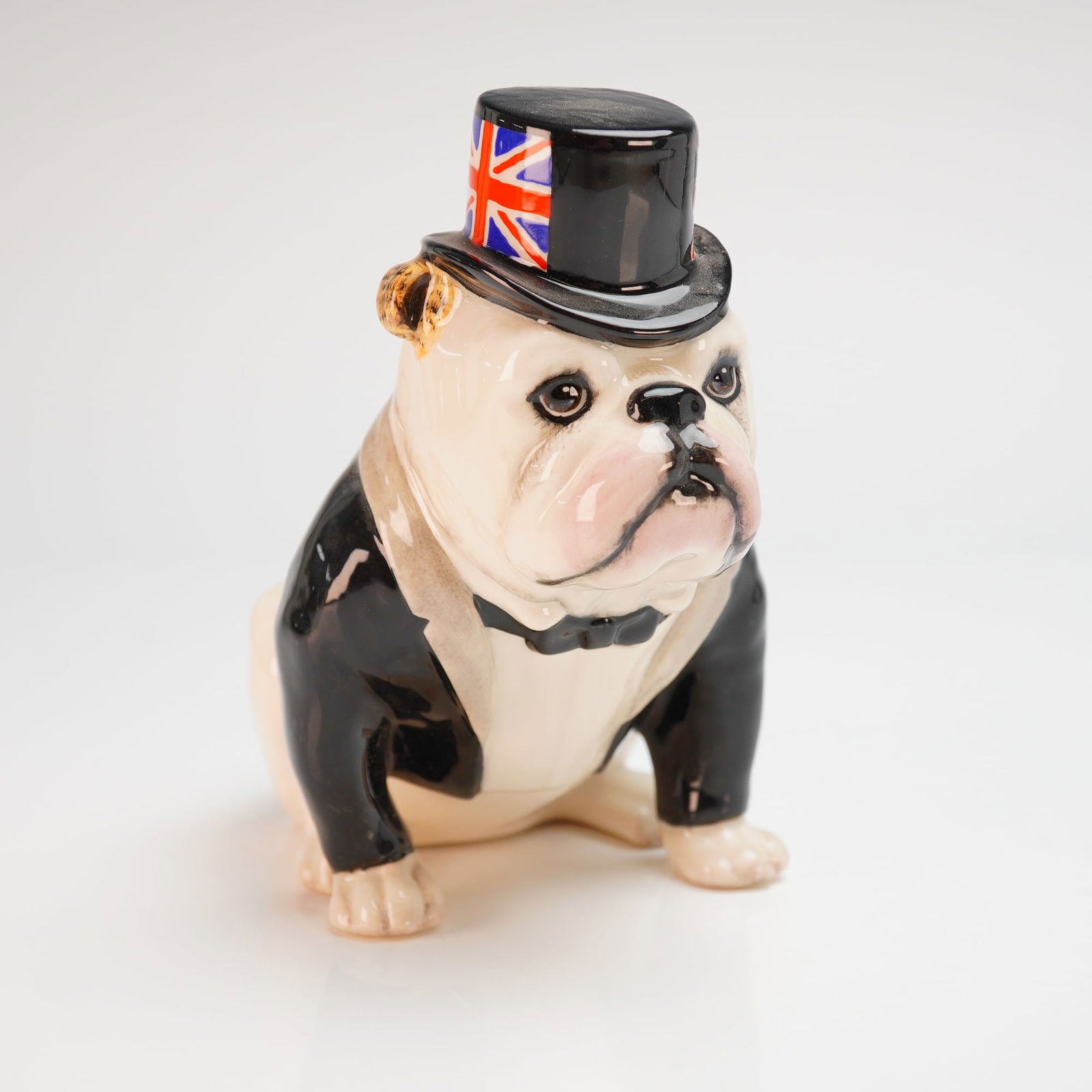 Royal Doulton The British Bulldog DA228 Limited Edition Figurine: A Royal Doulton glazed ceramic figurine titled The British Bulldog, model DA 228 (white). The figure depicts a seated bulldog dressed in a black tuxedo jacket with a bow tie and a black top hat adorne