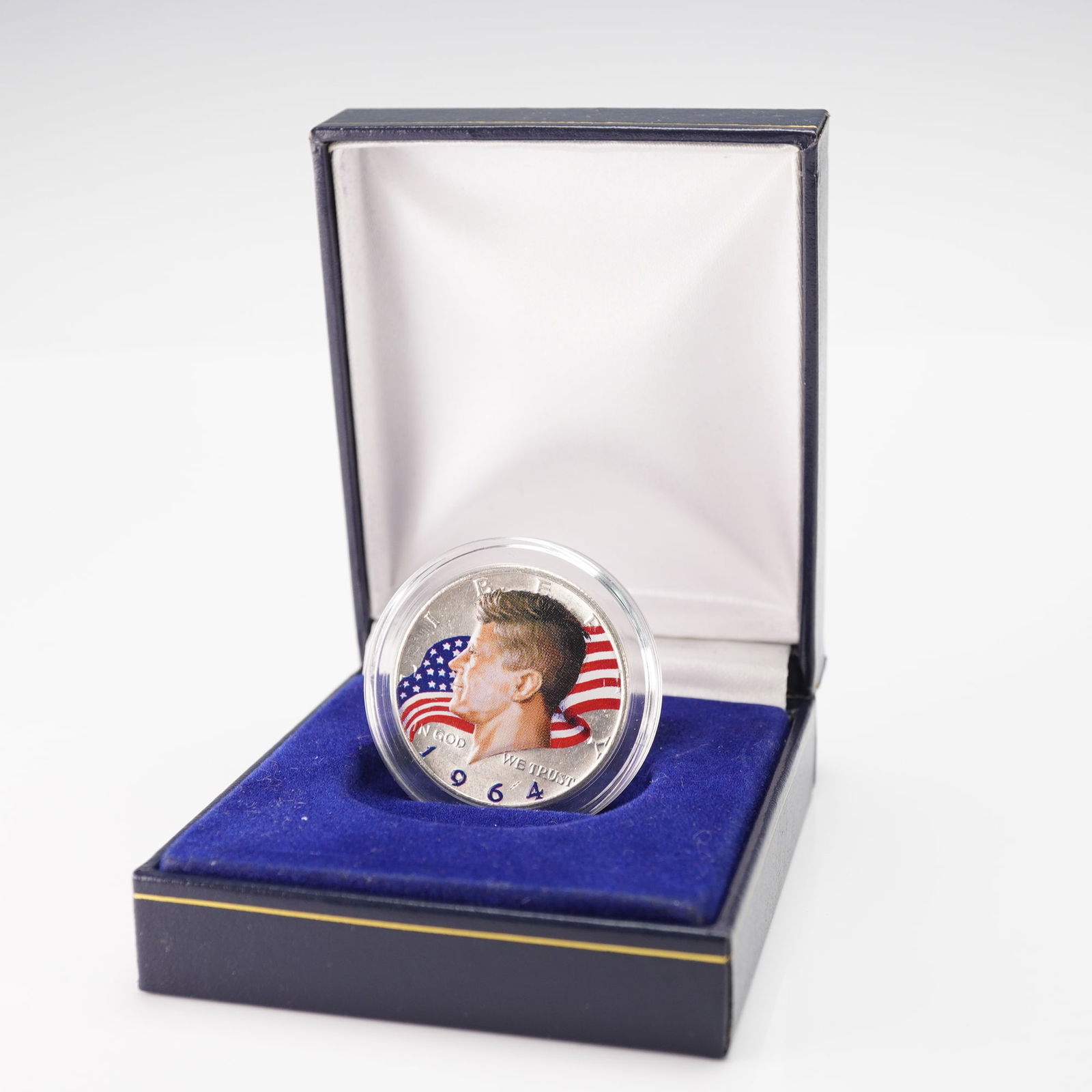 1964 US Kennedy Half Dollar Colorized Patriotic Design in Case: A 1964 United States Kennedy Half Dollar presented with a colorized patriotic design. The obverse depicts President John F. Kennedy against a full-color American flag background, while the reverse