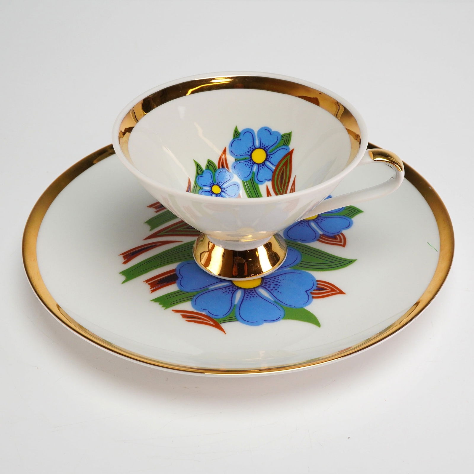 2pc Mitterteich Bavaria Porcelain Tea Set, Blue Floral: This is a two-piece set of Mitterteich Bavaria porcelain, comprising one pedestal-footed cup and one matching circular saucer. The set features a post-war or mid-century design aesthetic. The white ch