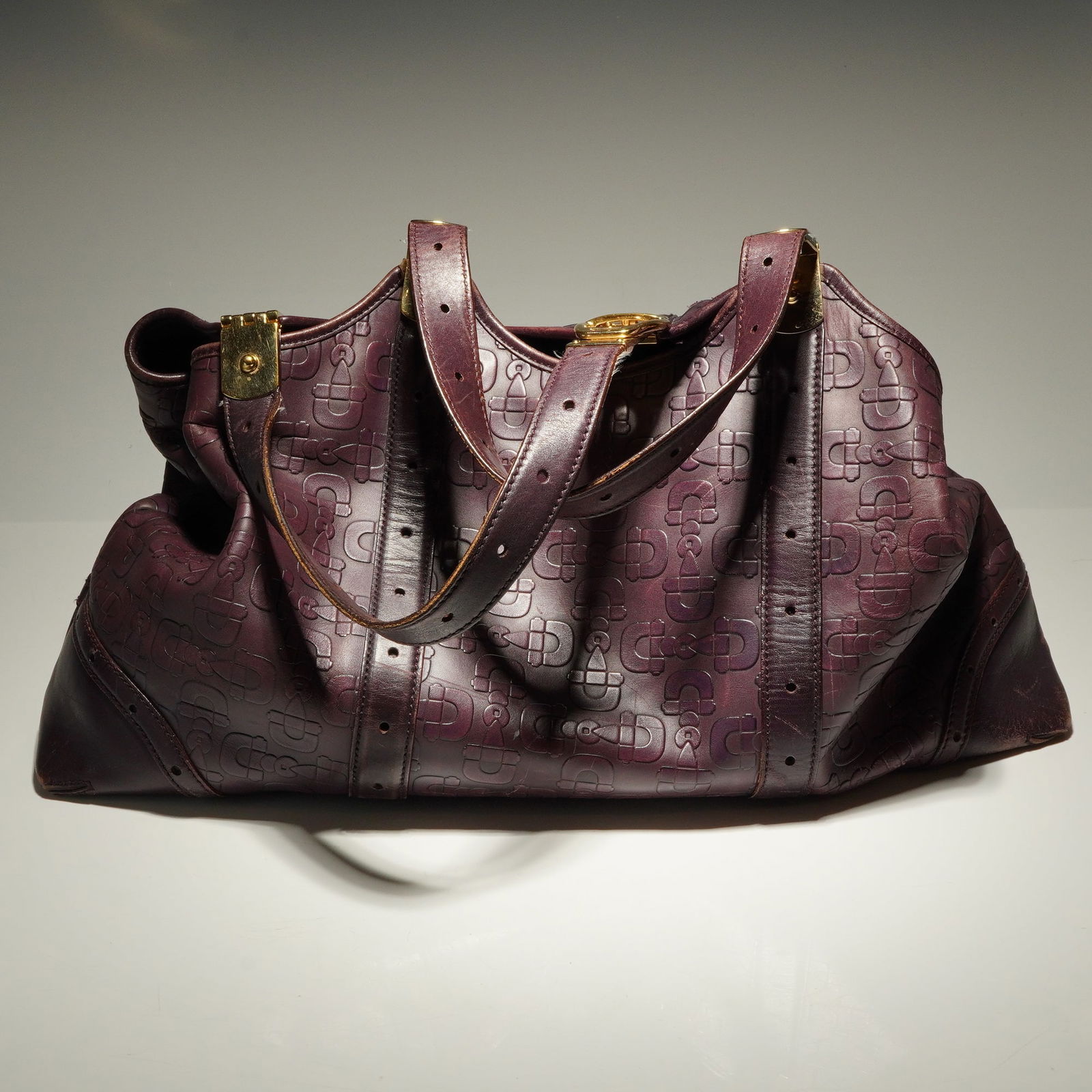 Gucci Italy Dark Purple Leather Horsebit Embossed Tote Bag: This Gucci tote bag is crafted in Italy from rich dark purple leather featuring an elegant horsebit embossed design. Finished with gold-tone hardware, this timeless Gucci piece blends classic equestri