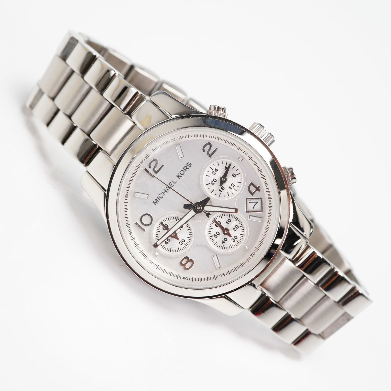 Michael Kors Runway Chronograph MK7325 Woman's Watch: A Michael Kors Runway Chronograph Woman's Watch, identified as model MK7325. This contemporary wristwatch is constructed entirely of polished and brushed stainless steel. The watch features a silver/o