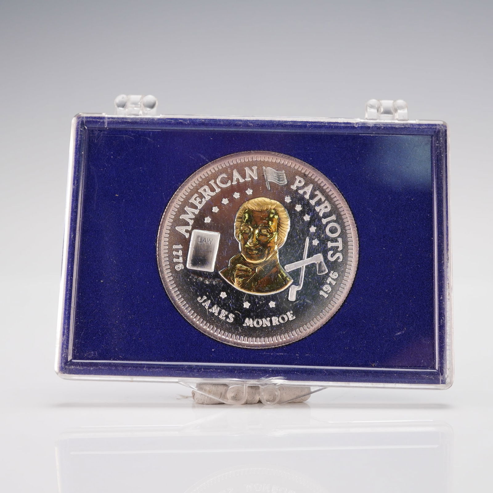 1976-L James Monroe American Patriots Silver and Gold Bullion: A James Monroe portrait on the obverse with stars, a LAW book, and quill, inscribed AMERICAN PATRIOTS, 1776, and JAMES MONROE. The reverse displays a wreath surrounding the inscriptions VINCIT AMOR PA