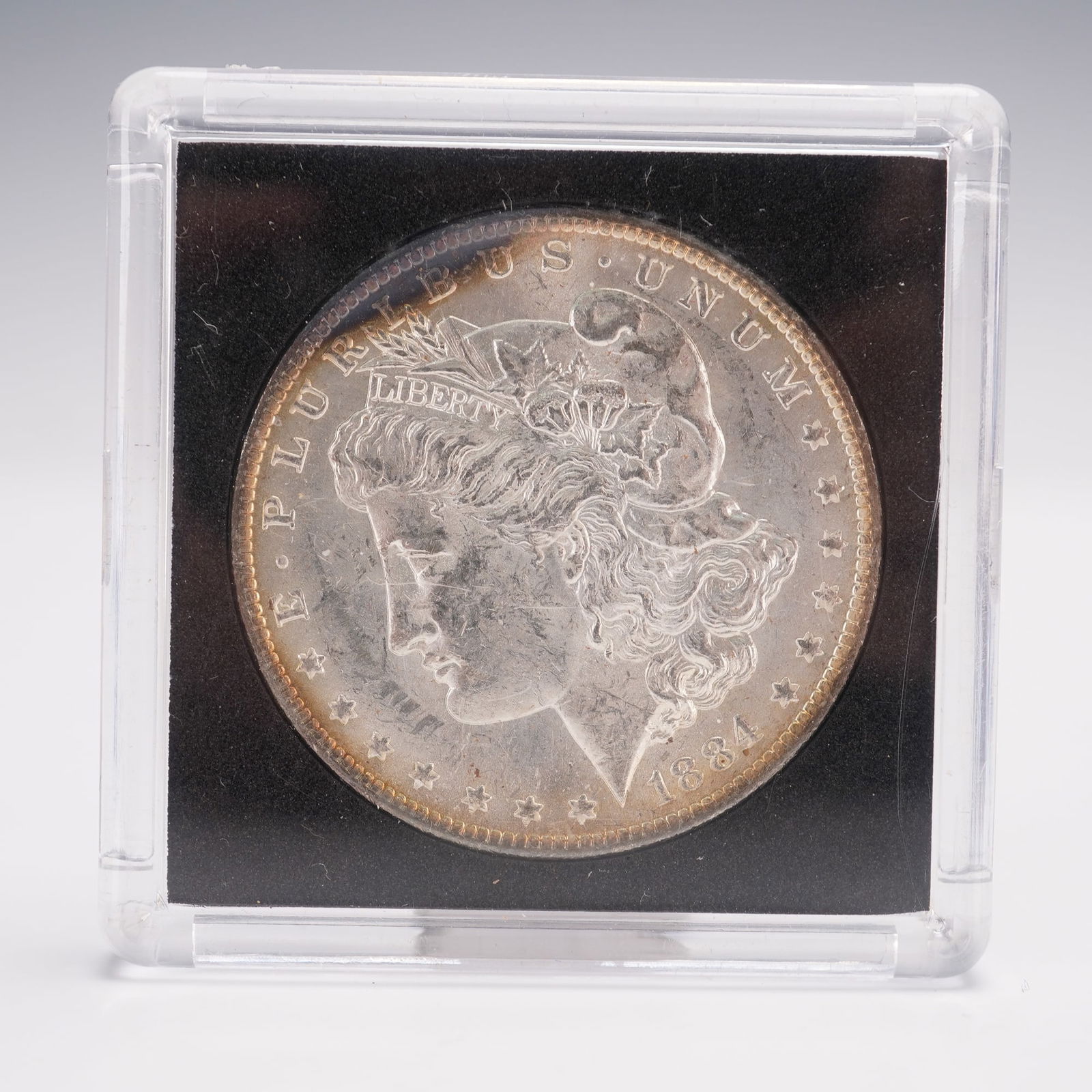 1884-O Morgan Silver Dollar: Struck at the New Orleans Mint. The obverse features the profile of Liberty facing left, wearing a Phrygian cap adorned with wheat and cotton, inscribed with the word LIBERTY, surrounded by the legend