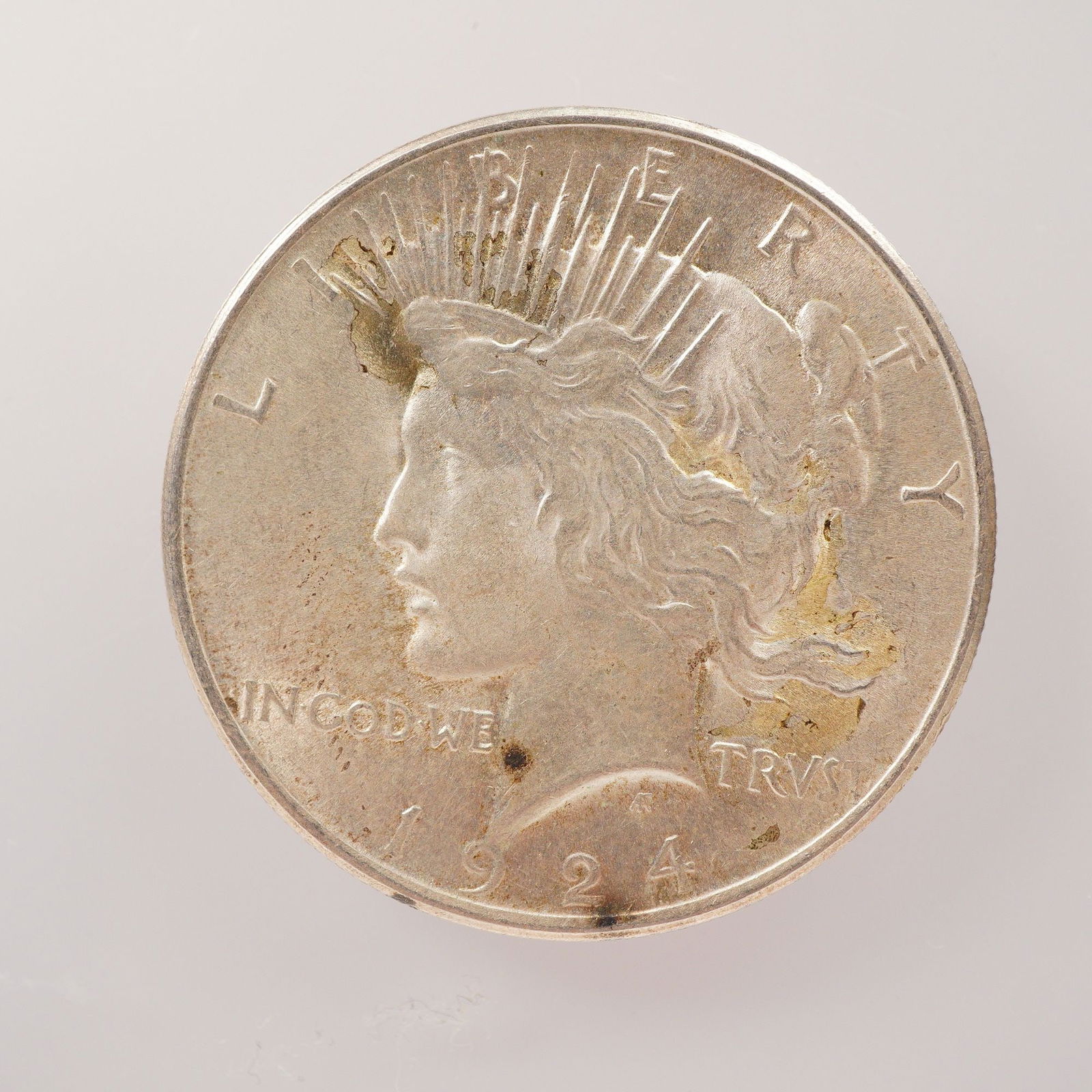 1924 Peace Silver Dollar Coin: The obverse displays a capped head of Liberty facing left surrounded by LIBERTY, IN GOD WE TRVST, and the year 1924 below. The reverse depicts an eagle standing right on a rock, wings folded, seen