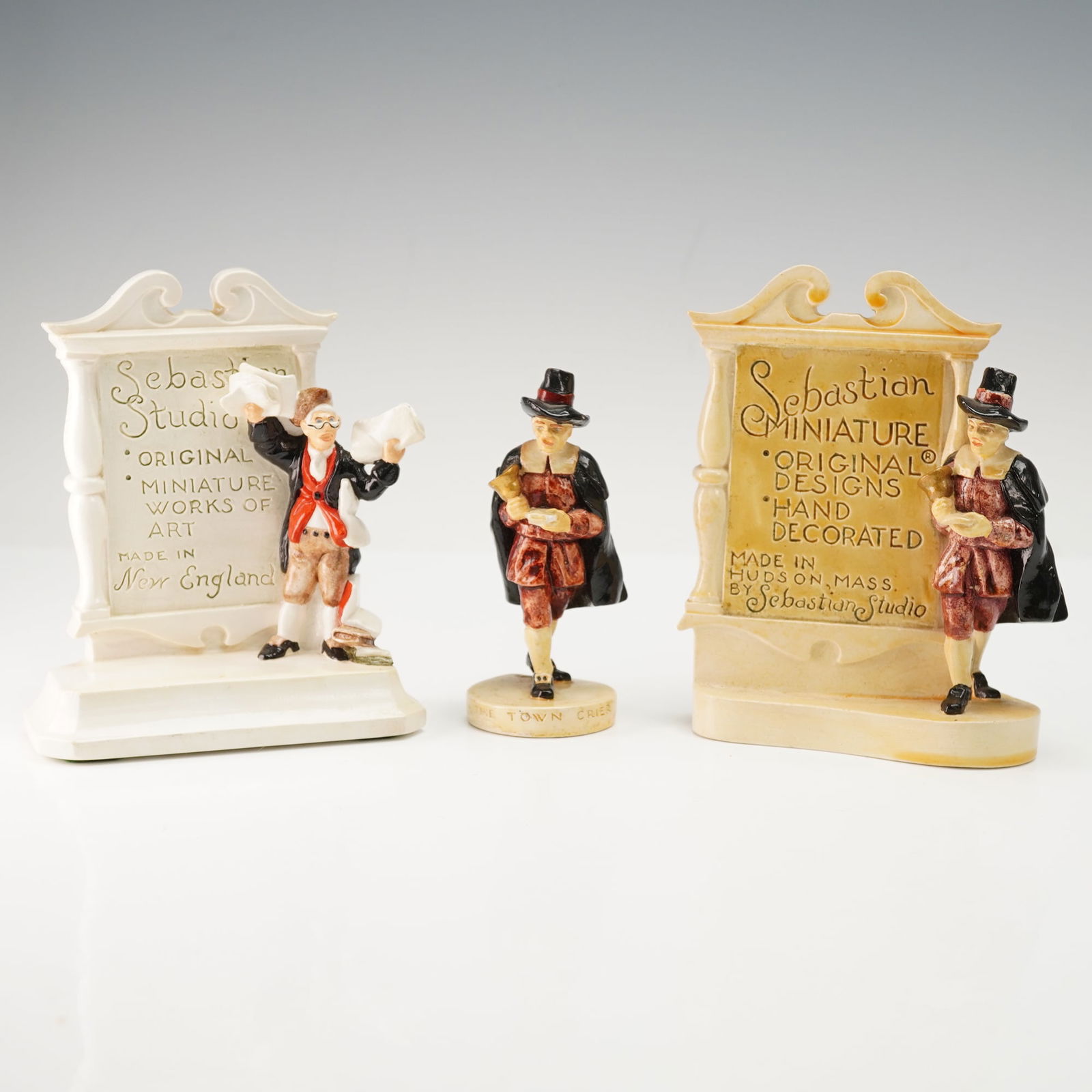 3pc Sebastian Miniatures Figurine and Dealer Advertising Plaques: Grouping of three hand-cast and hand-painted Sebastian Miniatures including one figure titled The Town Crier along with two dealer advertising plaques. Each plaque bears the company name and