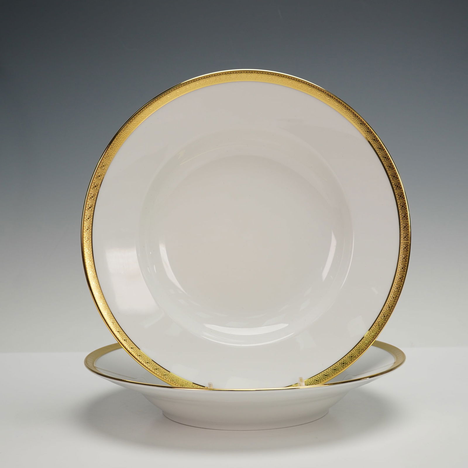 2pc Richard Ginori Gilt Trim Soup Bowls: Featuring a white ground accented by an elegant, wide gilt rim, each bowl displays a smoothly contoured, gently curved interior designed for refined service. The exterior maintains clean, balanced
