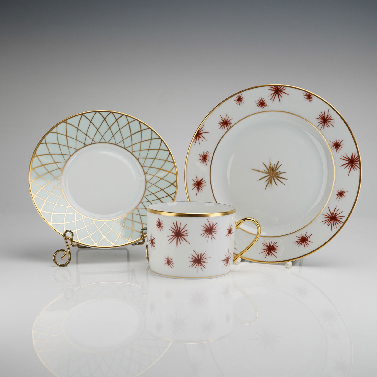 A Trio of Bernardaud Etoile Porcelain Flat Cup, Saucer, and Plate: A three-piece grouping of contemporary Bernardaud porcelain dinnerware in the Etoile (Star) pattern. This lot consists of a flat cup, a saucer, and a plate, consistent with a 3pc set configuration.