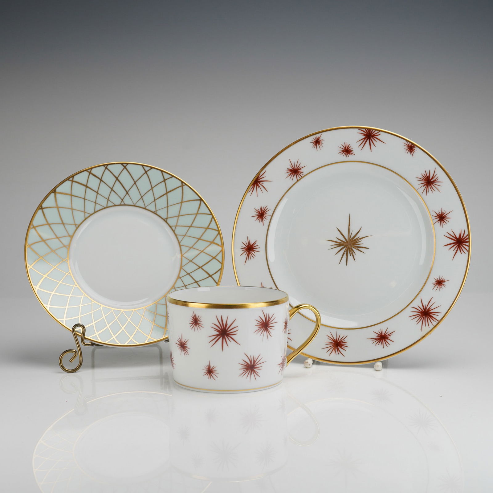 Three-Piece Bernardaud Etoile Flat Cup, Saucer, and Plate Set: A three-piece set of Bernardaud porcelain dinnerware in the Etoile pattern. This lot comprises a flat cup, a saucer, and a bread and butter plate, each piece featuring the backstamp. The set is
