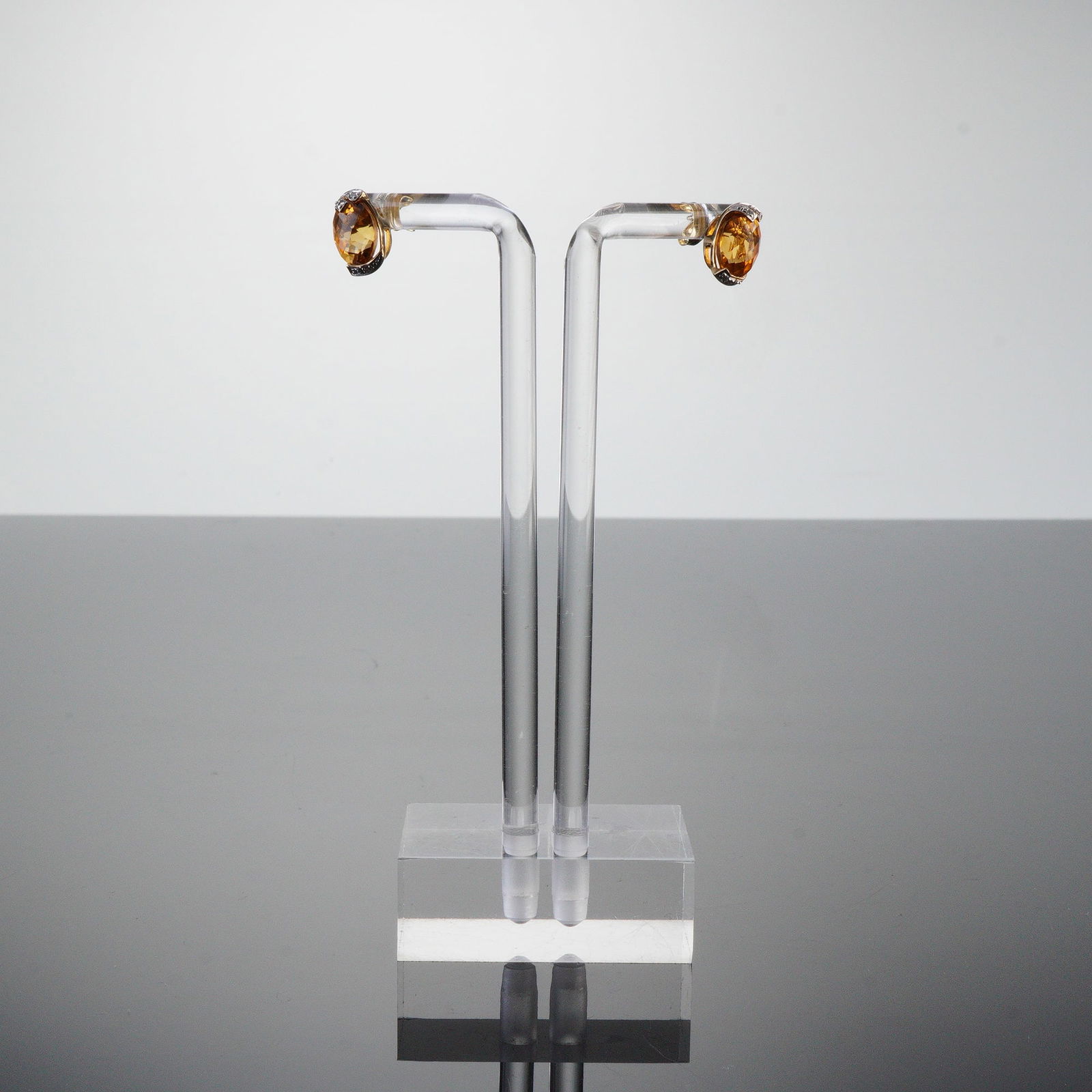 10K Gold and Amber-Colored Gemstones Stud Earrings: A pair of 10K gold stud earrings featuring prominent, oval-faceted, amber-colored citrines set in a mixed-gold and clear stones forming decorative cut-outs. The reverse of the earring is stamped 10K,