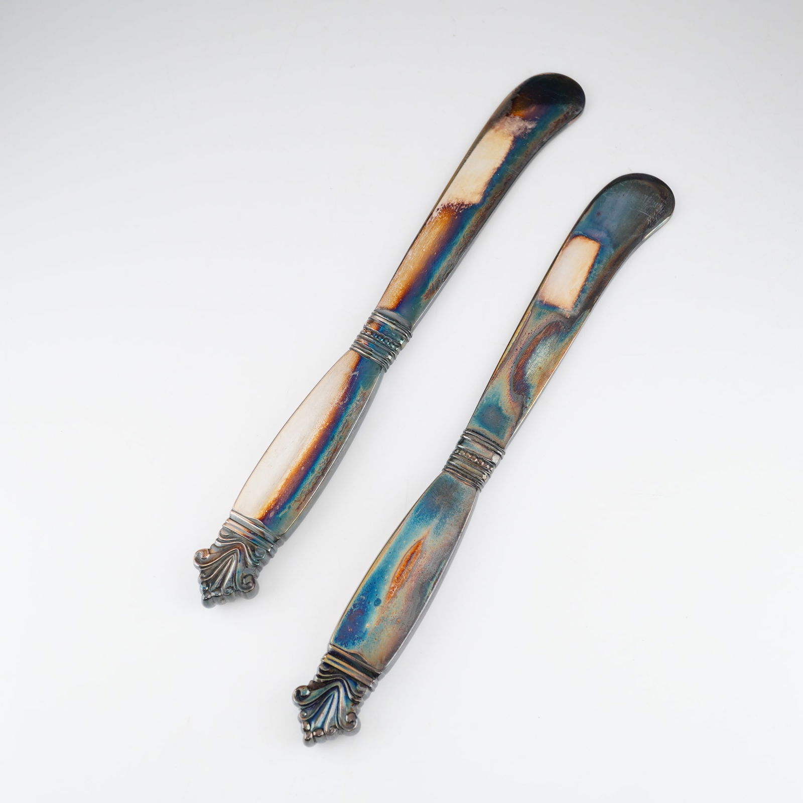 2pc Georg Jensen Sterling Silver Butter Spreaders, Acanthus: This pair of sterling silver spreaders is designed by Johan Rohde for Georg Jensen. Each piece features a short, rounded blade and a decorative handle characterized by a flared, stylized terminal and