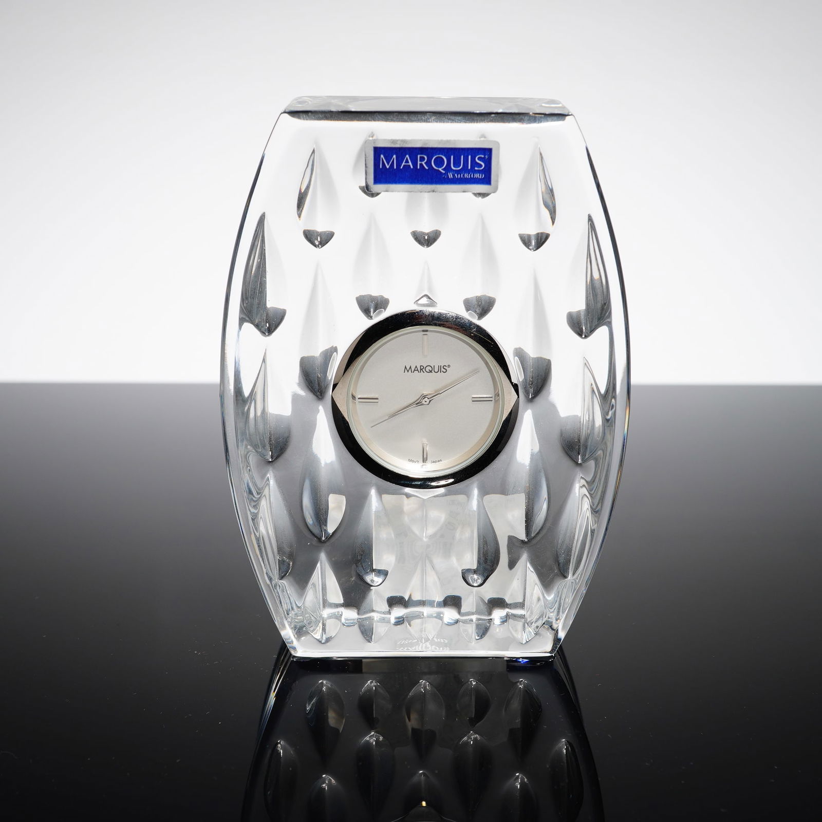 Marquis by Waterford Crystal Desk-Table Clock, Rainfall: The piece features an arched rectangular body of clear lead crystal with a surface-cut teardrop motif. The central circular clock face contains a silver-tone dial with baton hour markers, matching han
