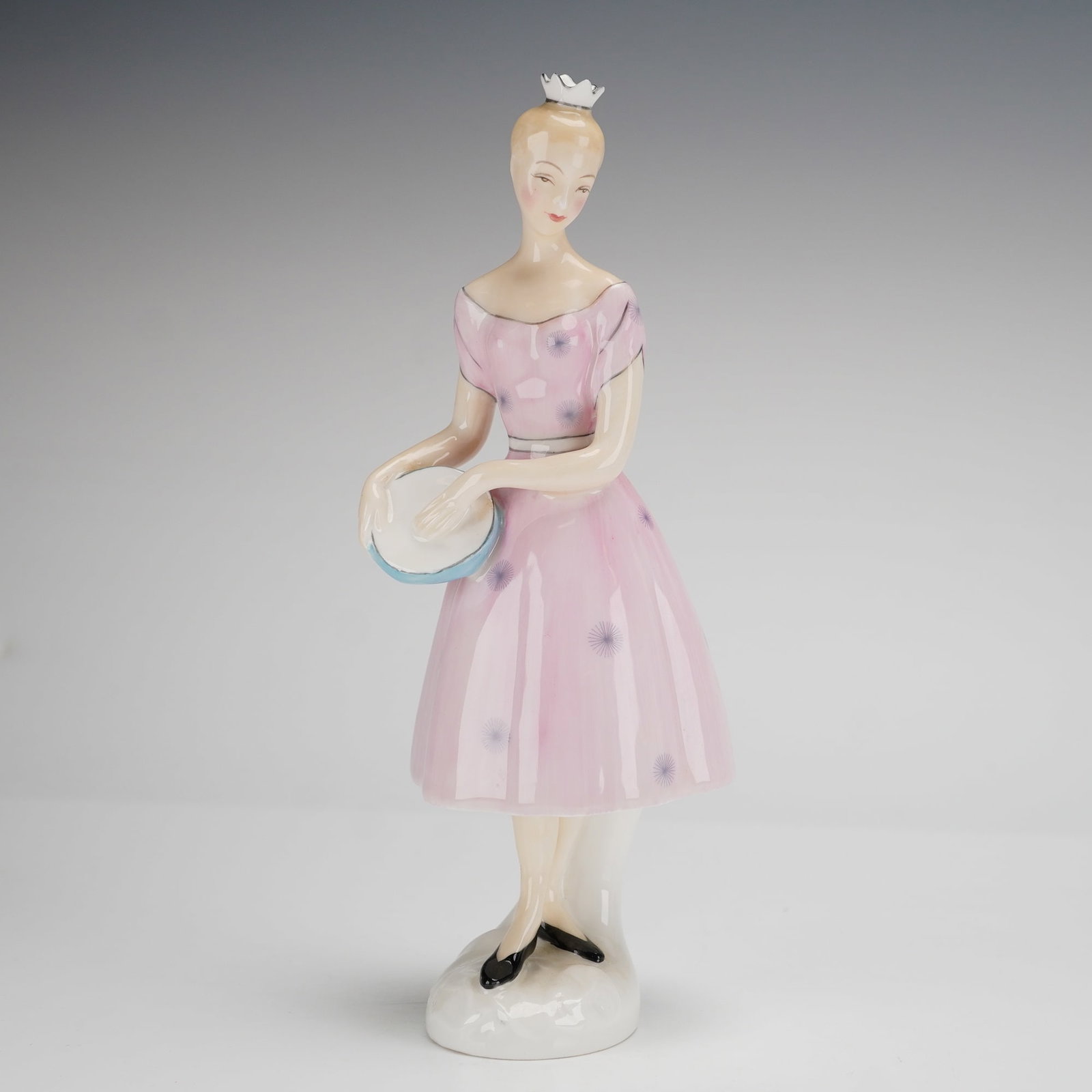 Royal Doulton Columbine HN 2185 Figurine: This Royal Doulton bone china figurine, titled Columbine (HN 2185), depicts a slender female figure in a standing pose. The figure is modeled wearing a small white crown and a pink off-the-shoulder dr