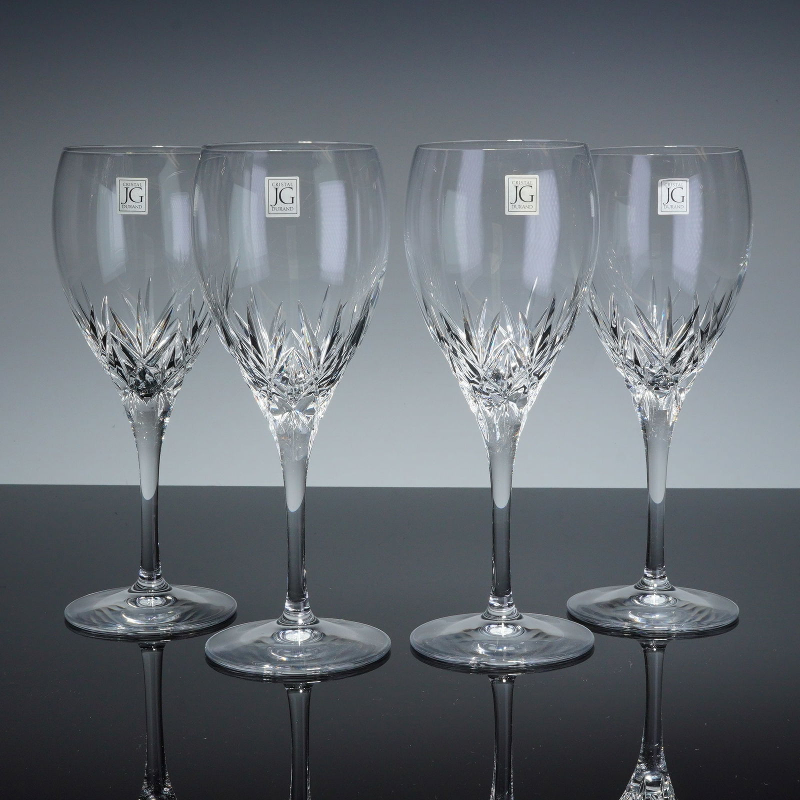 Set of Four JG Cristal Durand Cut Crystal Wine Glasses: This set of four wine glasses from JG Cristal Durand is crafted from clear cut crystal. Each glass features a tapered bowl decorated with a sharp, multi-faceted starburst cut pattern at the base, tran