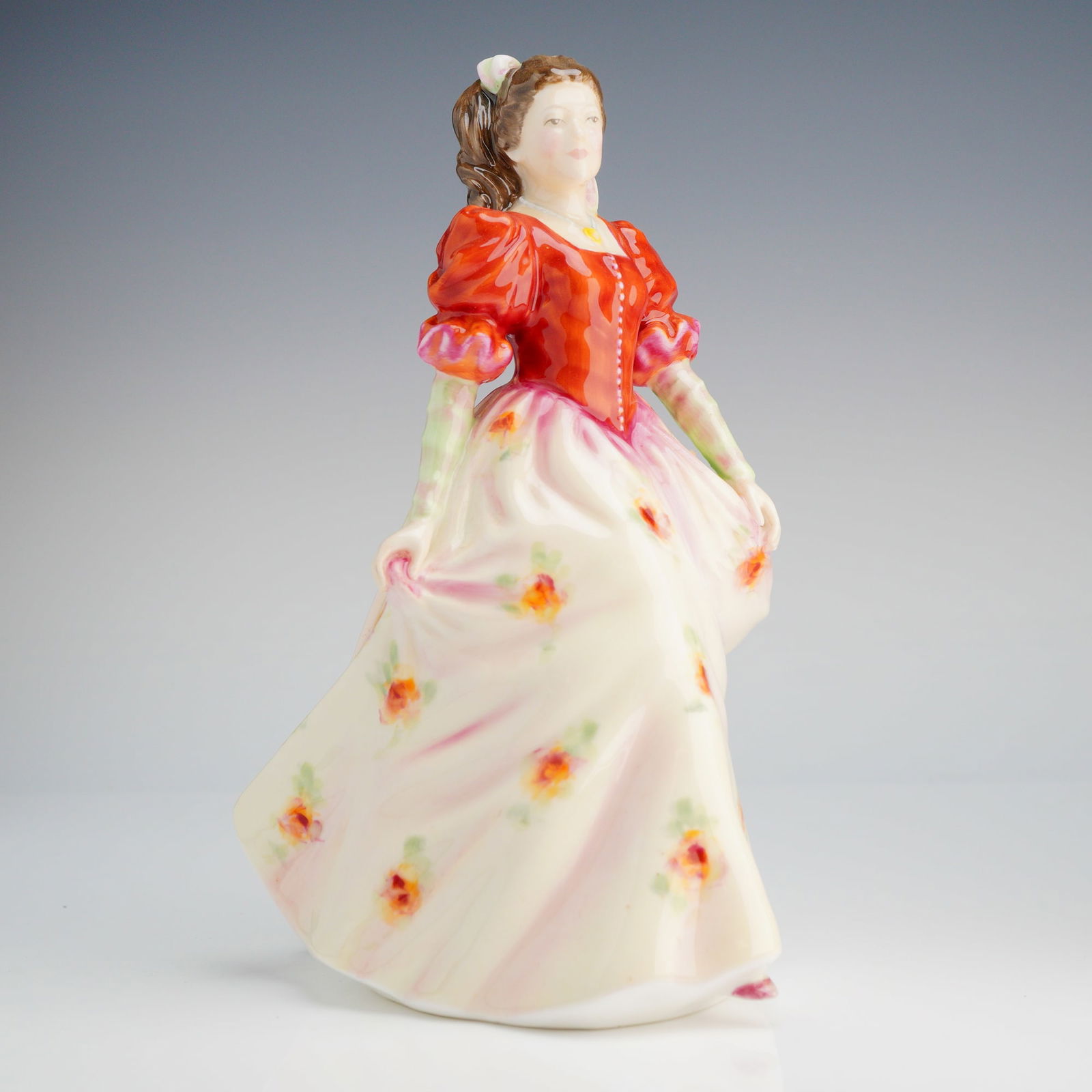 Royal Doulton Figurine, Kate HN3765: The figure was modeled by Mada M. Pedley and is copyrighted 1995. The figurine depicts a woman standing in a period-style gown. The garment features a reddish-orange bodice with puffed sleeves and a f