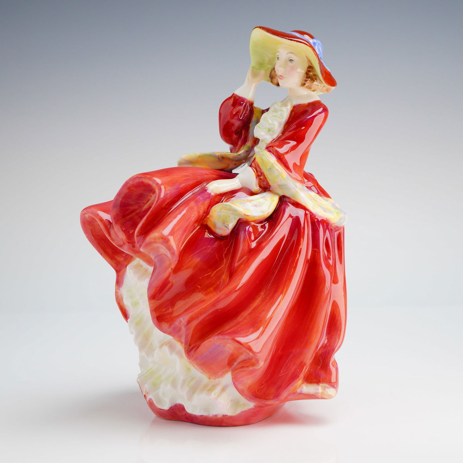 Royal Doulton Figurine, Top O' The Hill HN1834: A single Royal Doulton figurine, depicting a woman in a glossy red dress and wide hat, marked COPR 1937 and DOULTON & CO. LIMITED on the base. Dimensions: 5.00"L x 4.50"W x 7.25"H Weight: 1.00 lb 4.00