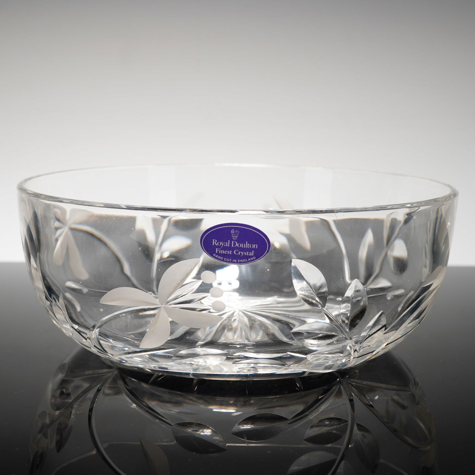 Royal Doulton Chloe Pattern Crystal Salad Bowl: A Royal Doulton crystal salad bowl in the Chloe pattern. This circular vessel is constructed of clear lead crystal and features hand-cut floral and foliate motifs. The design includes a starburst-cut