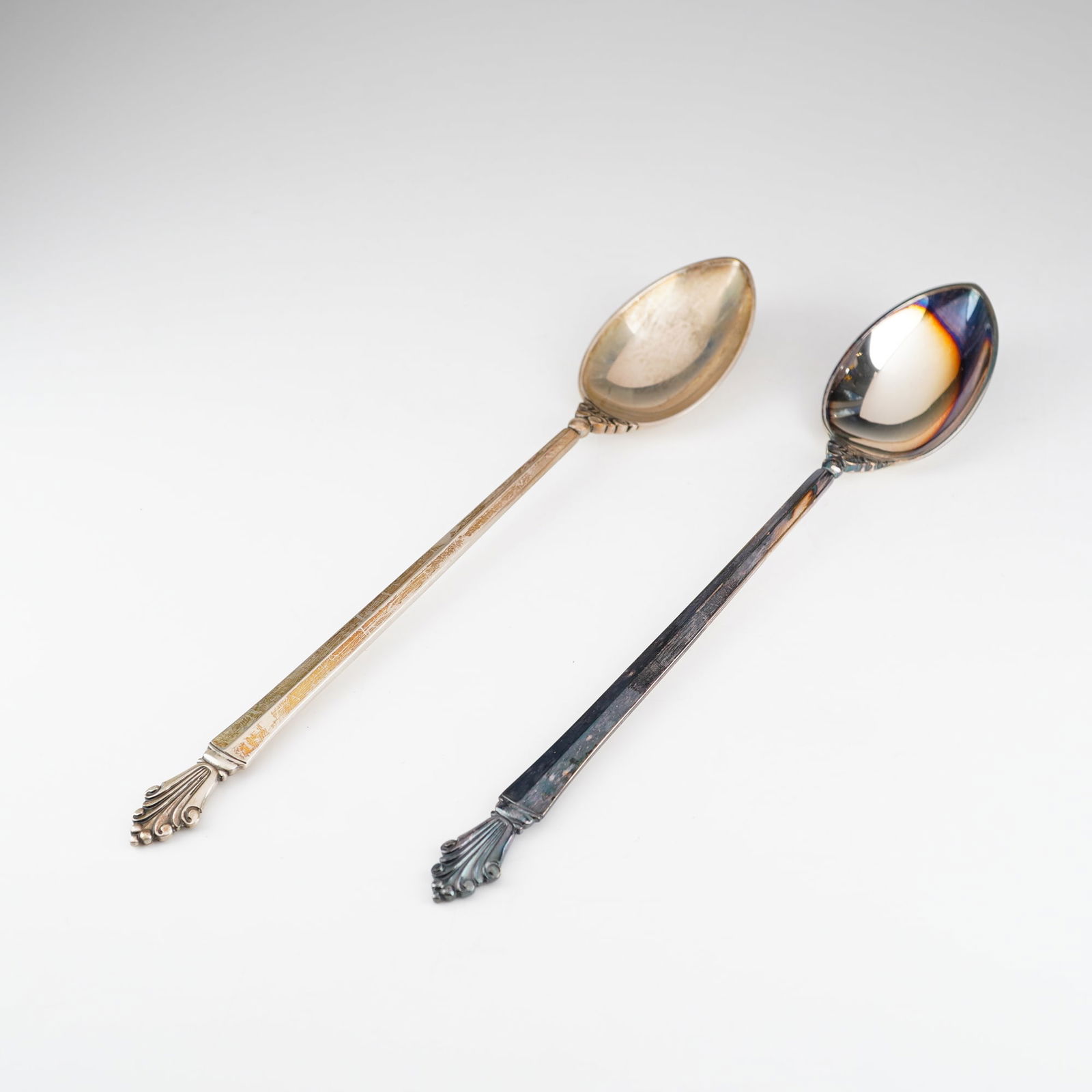 2pc Georg Jensen Sterling Silver Iced Tea Spoons, Acanthus: A pair of Georg Jensen sterling silver iced tea spoons in the Acanthus pattern designed by Johan Rohde. Each spoon features a long handle with a stylized foliate motif at the terminal and at the junct