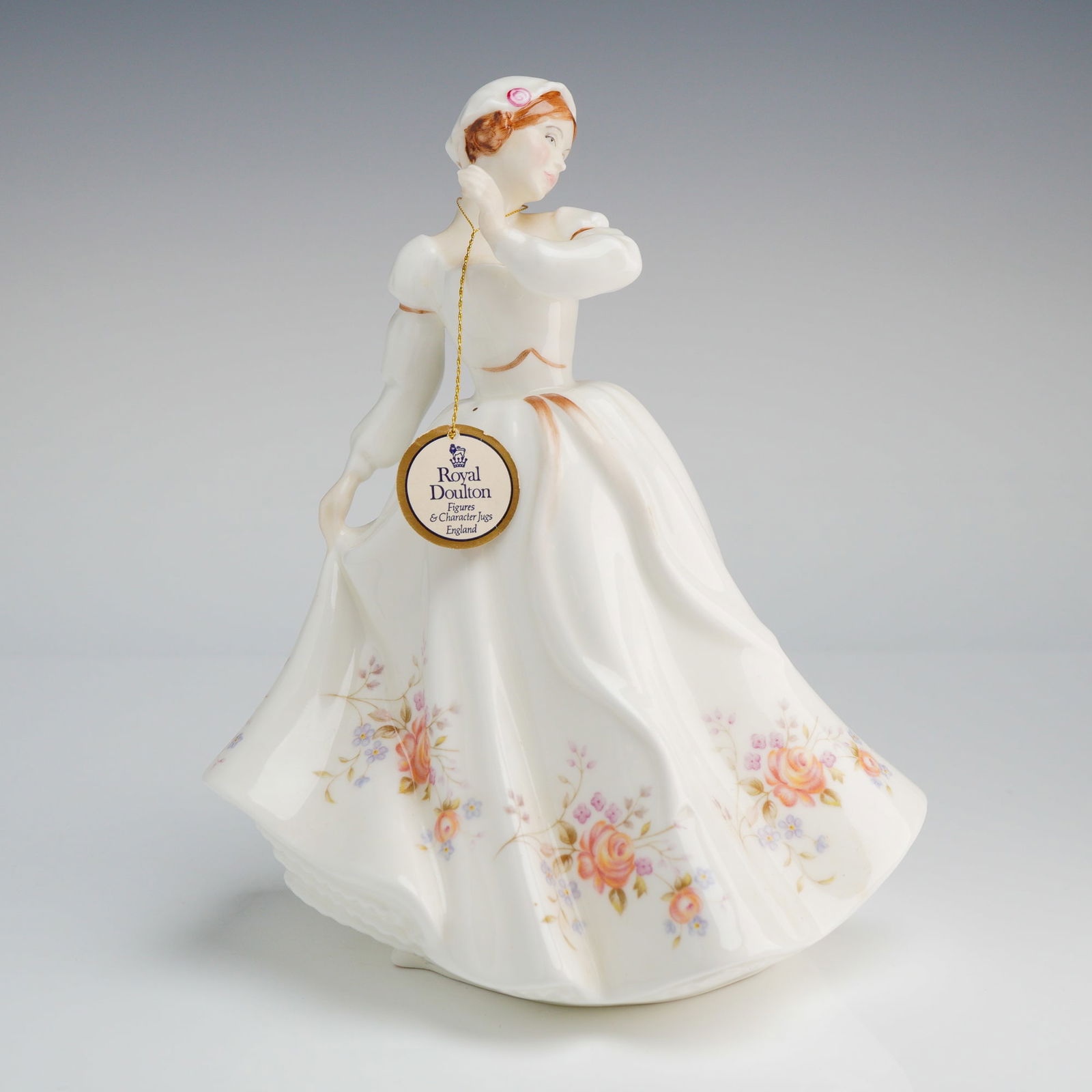 Royal Doulton Figurine Rosemary HN3143: The figure was modelled by P. Parsons and copyrighted in 1988. The figurine depicts a young woman standing in a flowing, long-sleeved white dress. The skirt is detailed with hand-painted floral motifs