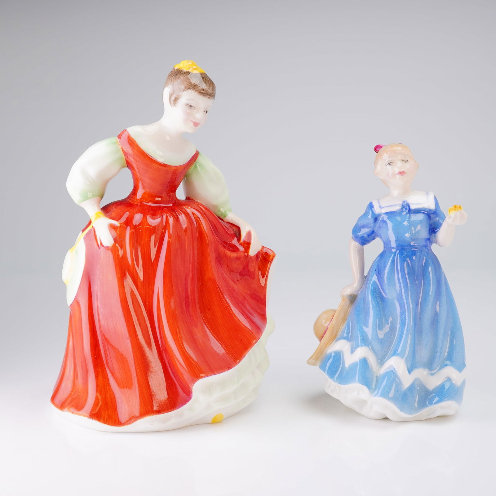 2pc Royal Doulton Figurines, Fair Maiden HN3606 and Posy For You HN2434: The first, larger figure is titled 'Fair Maiden,' and dated 1984. This figure is decorated predominantly in a vivid red gown with pale green accents. The second, smaller figure is titled 'A Posy For Y