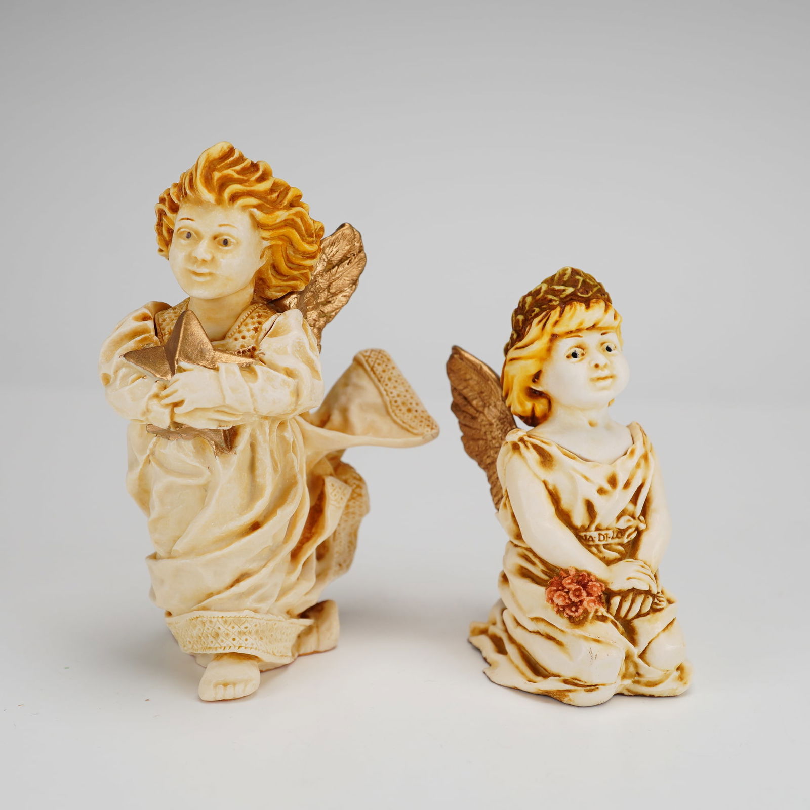 2pc Harmony Kingdom Box Figurines, Celeste & Fleur-de-lis Angel: Both pieces are designed with removable heads that reveal small interior compartments. The Celeste figurine depicts a standing angel in cream-colored robes holding a gold-tone star, while the Fleur-de