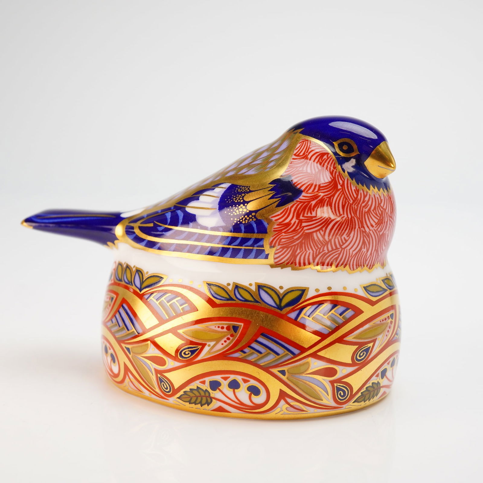 Royal Crown Derby Paperweight Nesting Bullfinch with Box: A Royal Crown Derby English fine bone china paperweight titled Nesting Bullfinch. The figurine is decorated in an Imari-style palette featuring cobalt blue and iron red with extensive gold gilding. Th