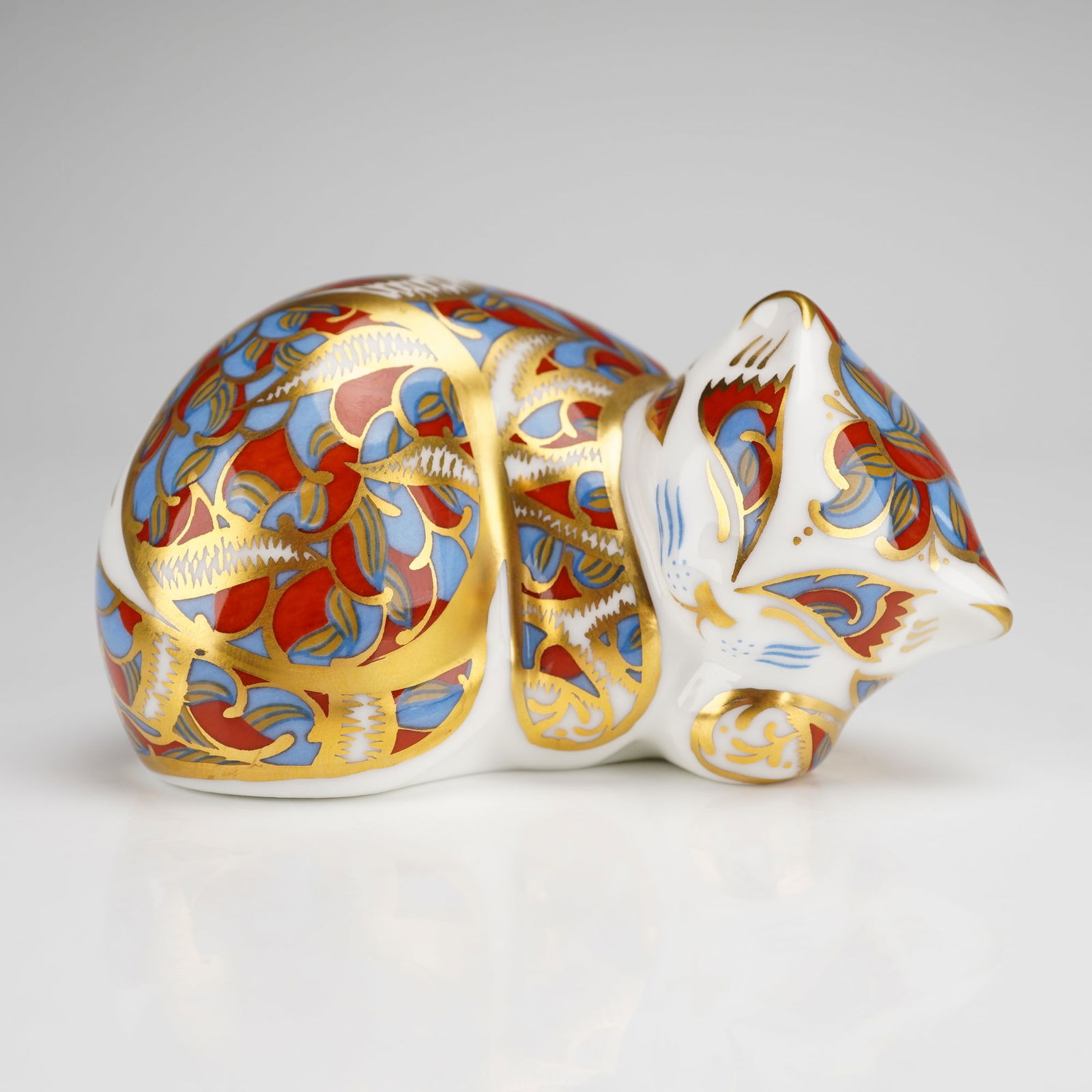 Royal Crown Derby Paperweight, Catnip Kitten: The piece is modeled in a curled, sleeping position and decorated in the traditional Imari style using a palette of cobalt blue and iron red. The decoration is accented with intricate gold gilding fea