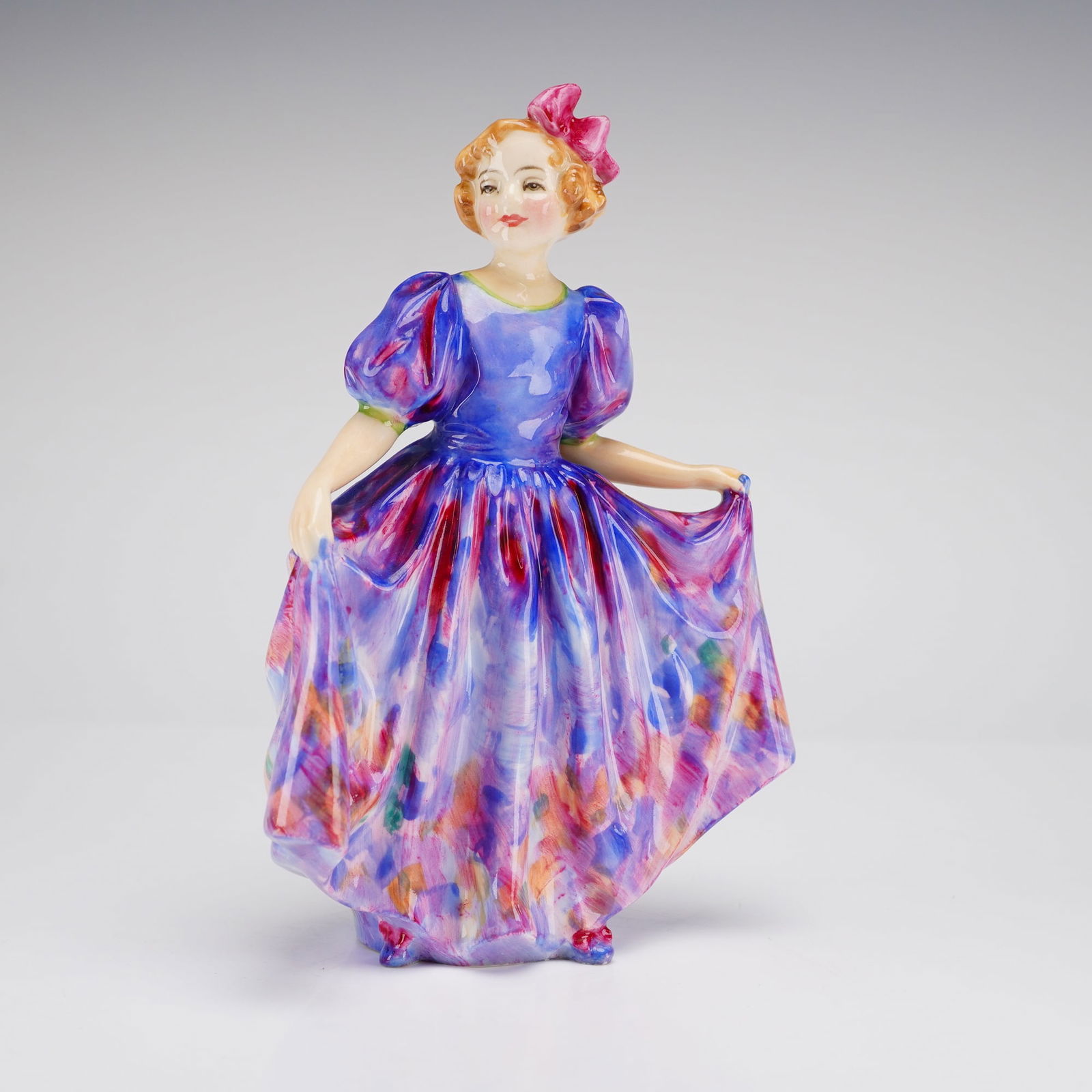 Royal Doulton Figurine Sweeting HN 1938: A glazed bone china figurine by Royal Doulton, depicting a young girl in a colorful dress with a bow in her hair. Decorated primarily in shades of blue, purple, and pink. The underside features the Ro