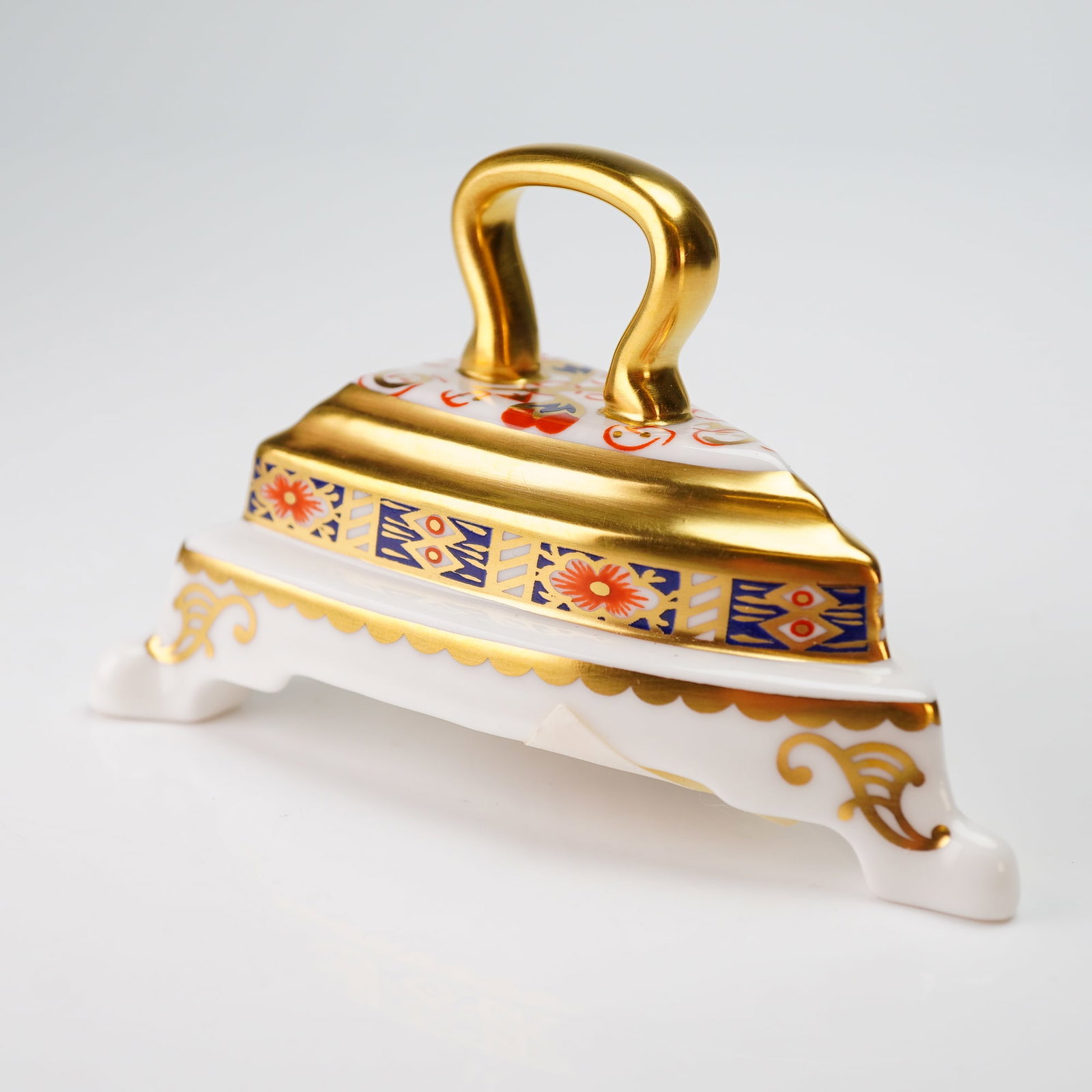 Royal Crown Derby Miniature Figurine, Iron on Stand Imari: A Royal Crown Derby fine bone china miniature flat iron and stand decorated in a traditional Imari style. The piece features cobalt blue, iron red, and gilt accents with a stylized floral and geometri