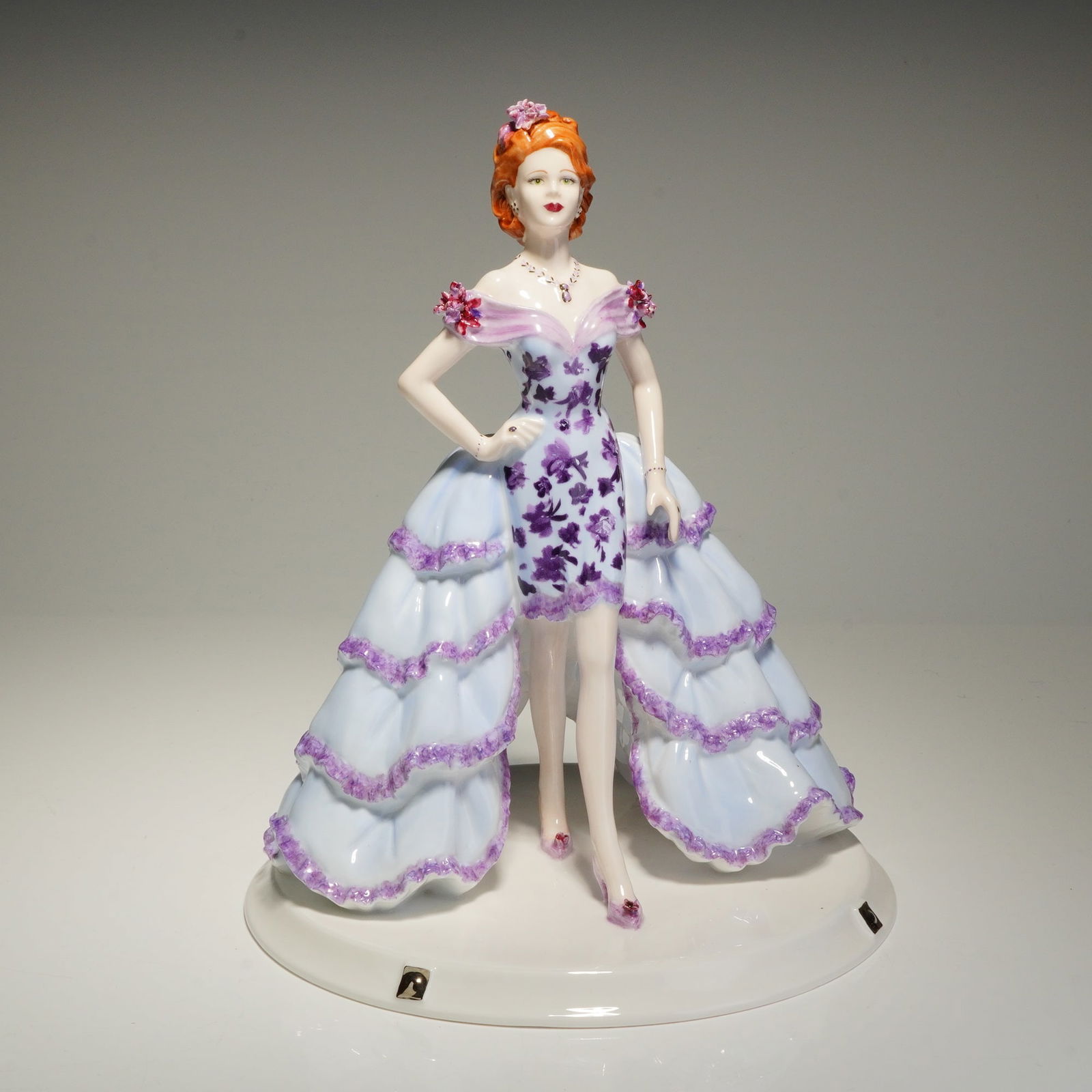 Coalport David Shilling Celebration Collection Figurine, Violet V.I.P.: This hand-decorated piece was modeled by Jack Glynn and designed by David Shilling. The figure is depicted with red hair and a floral-patterned dress featuring tiered ruffles in light blue and
