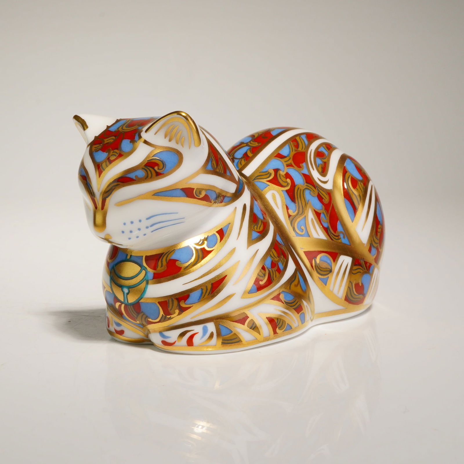 Royal Crown Derby Contented Cat Paperweight: A Royal Crown Derby English bone china paperweight in the Contented Cat pattern. The figurine is decorated in the traditional Imari style with a palette of cobalt blue and iron red, accented with 22-k