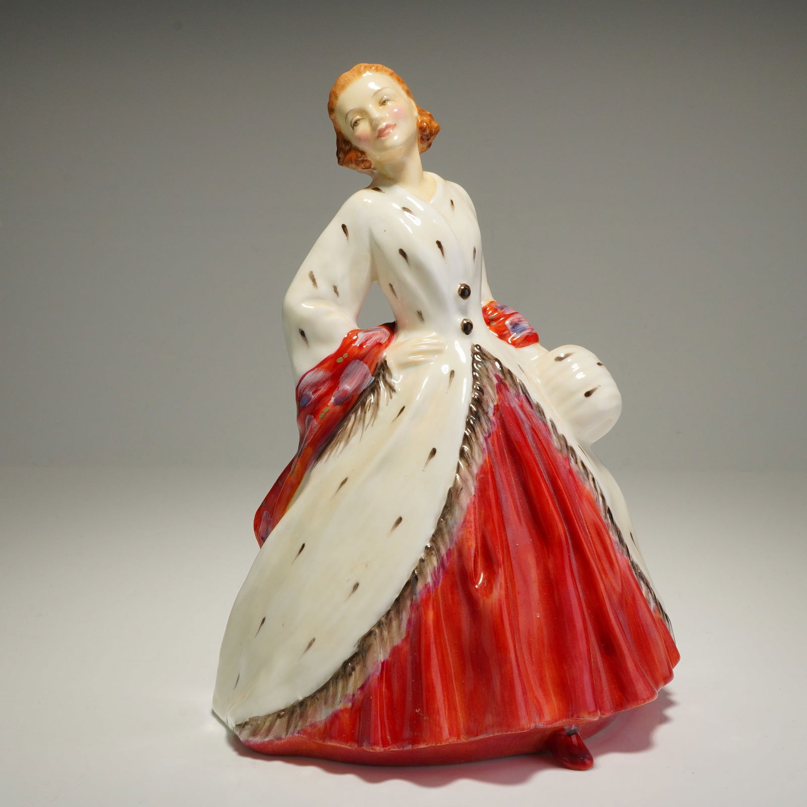 Royal Doulton Figurine, The Ermine Coat HN1981: A Royal Doulton bone china figurine titled The Ermine Coat, model HN1981. The hand-painted figure depicts a woman in mid-20th-century attire, featuring a floor-length white coat with dark ermine spots
