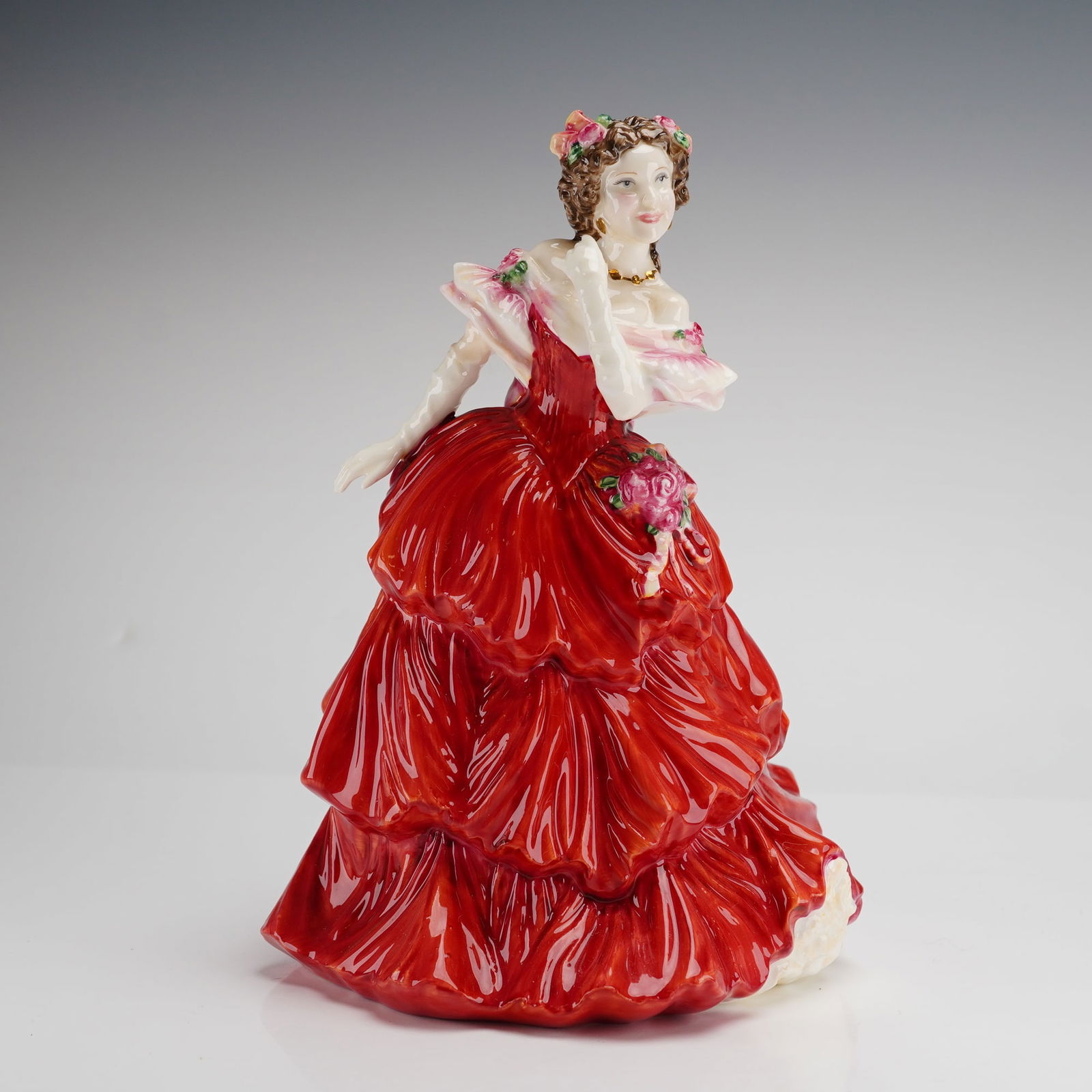 Royal Doulton Joy HN 4054 Bone China Figurine: A Royal Doulton hand-decorated bone china figurine titled Joy, model number HN 4054. The figure depicts a woman in a red tiered ballgown with a pink shawl tied in a bow at the back. The subject featur