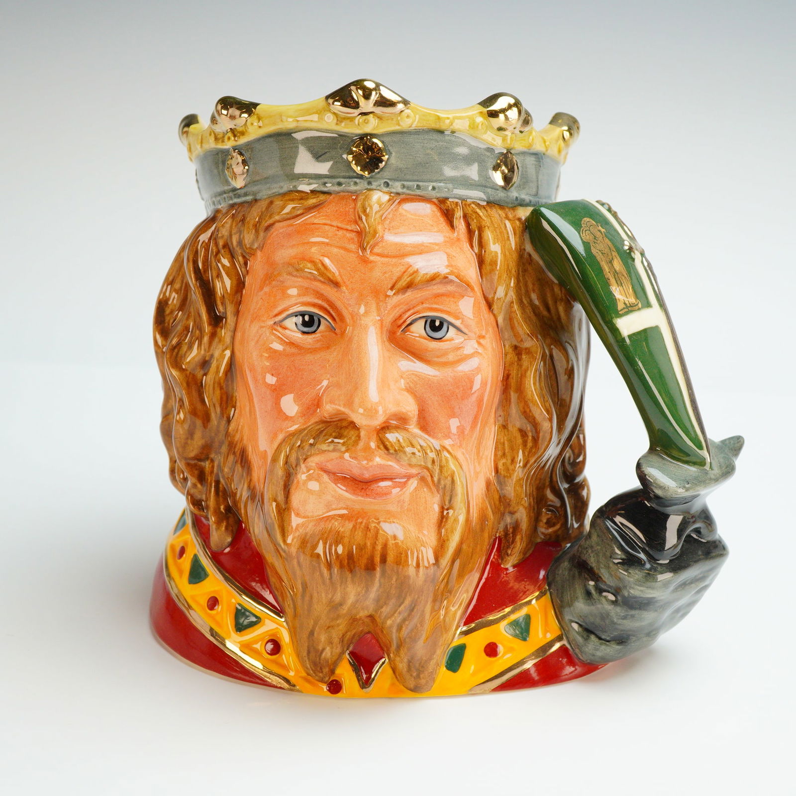 Royal Doulton Large Character Jug, King Arthur D7055: This large, hand-decorated ceramic jug was designed by Robert Tabbenor and issued in 1996. The figure is modeled with long brown hair, a beard, and a crown featuring metallic gold accents. The charact