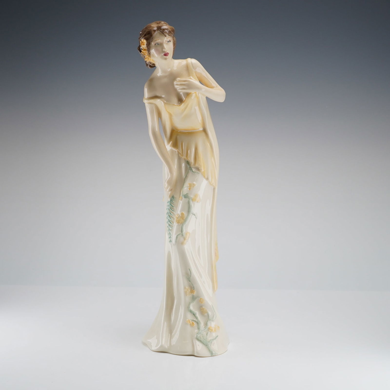 Royal Doulton Sculpture, Sweet Dreams HN4193: The piece is modeled in a style evocative of late Art Deco or Neoclassical Revival, depicting a standing female figure draped in a flowing, cream and pale-yellow gown. The gown is accented with hand-p