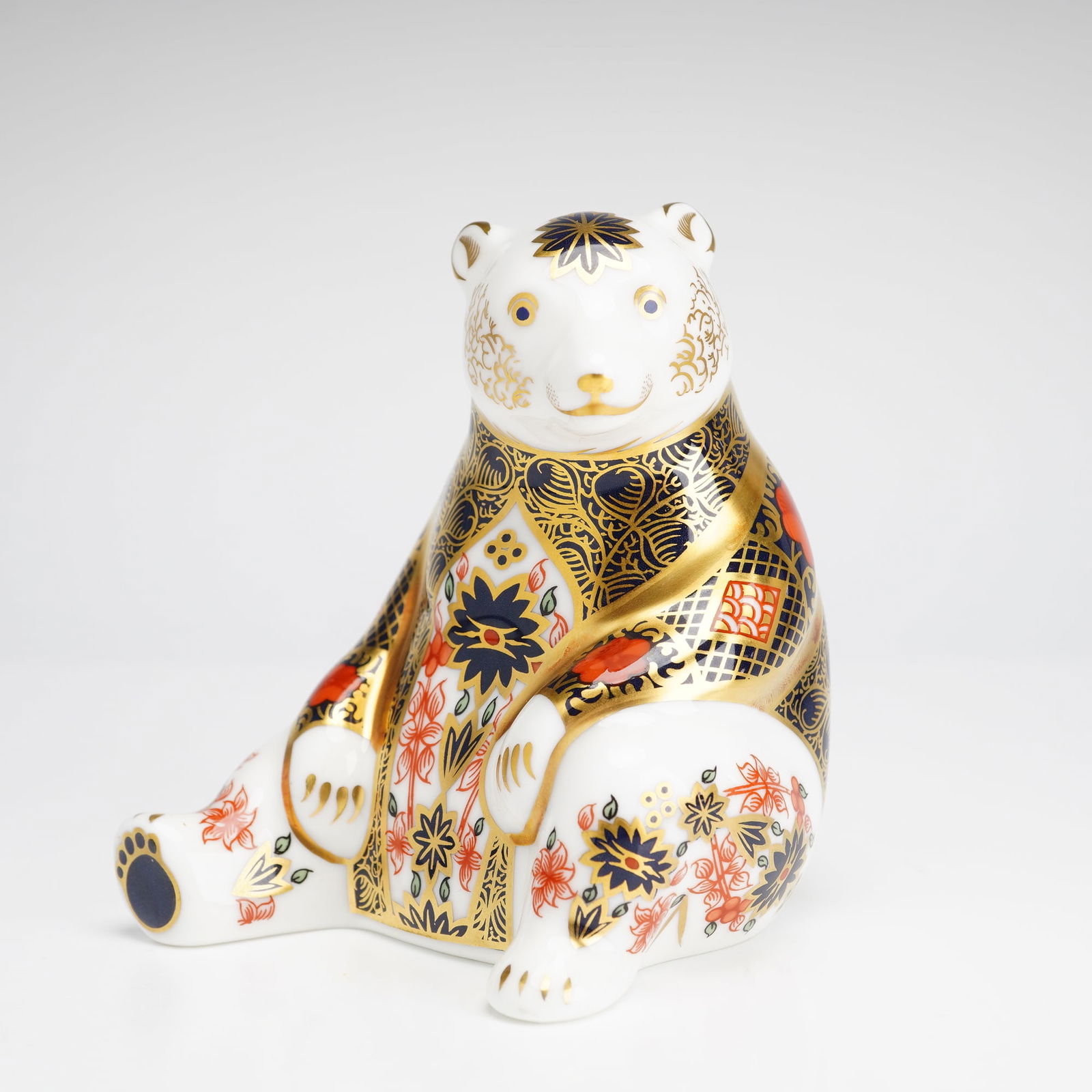 Royal Crown Derby Old Imari Honey Bear Paperweight: A Royal Crown Derby English bone china paperweight in the form of a Honey Bear, decorated in the traditional Old Imari pattern. The seated figure is finished in a palette of cobalt blue and iron red w