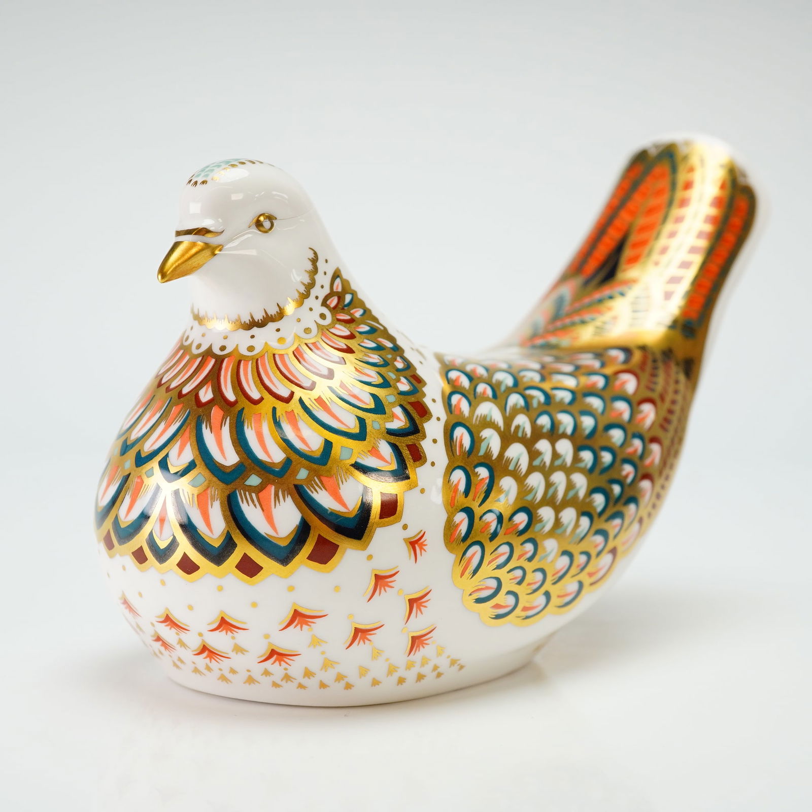 Royal Crown Derby Paperweight, Turtle Dove: The figurine is decorated in a traditional Imari style with intricate patterns in iron-red and cobalt blue, accented by rich gold gilding. The design features detailed, stylized feathering across the