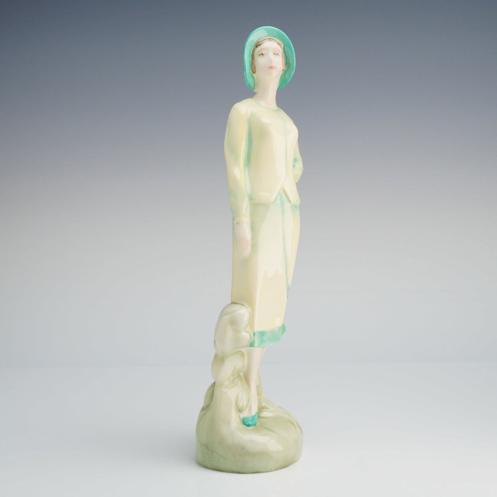 Royal Doulton Figurine, Sophie HN3790: The figure depicts a woman in a full-length suit and cloche hat, executed in an Art Deco style referencing 1920s fashion. The figure is hand-decorated primarily in pale creamy yellow/ivory, contrasted
