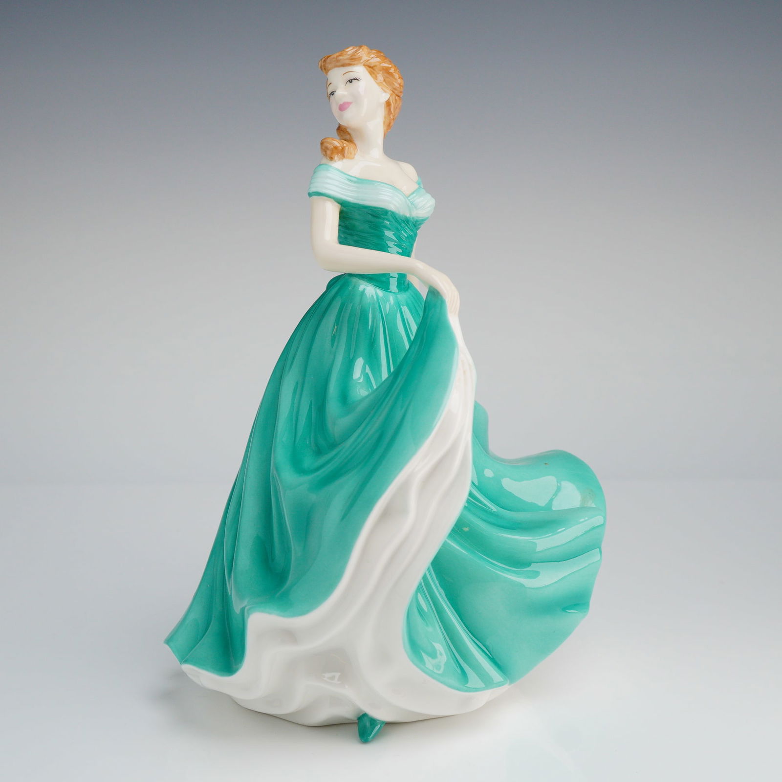 Royal Doulton Pretty Ladies Figurine, All My Love HN4747: The figure depicts a standing lady in a flowing, off-the-shoulder evening gown executed primarily in a glossy teal or turquoise green glaze, contrasting with a wide white underskirt visible beneath th