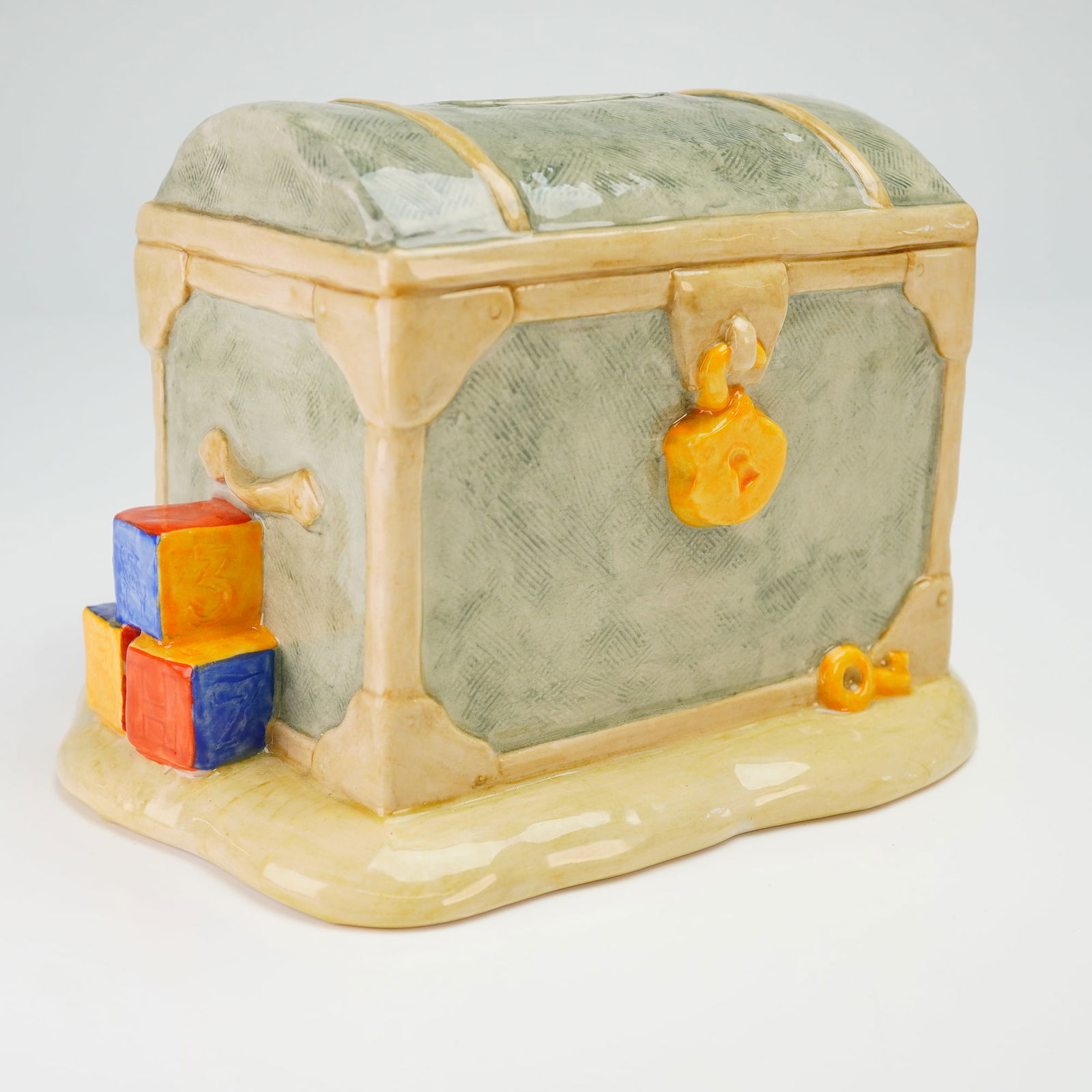 Brambly Hedge by Royal Doulton Money Bank, Wilfred and the Toy Chest DBH35: This hand-decorated figurine depicts the character Wilfred the mouse wearing a wide-brimmed hat and overalls, standing beside a green domed toy chest and holding a floral-patterned cloth. The chest fe