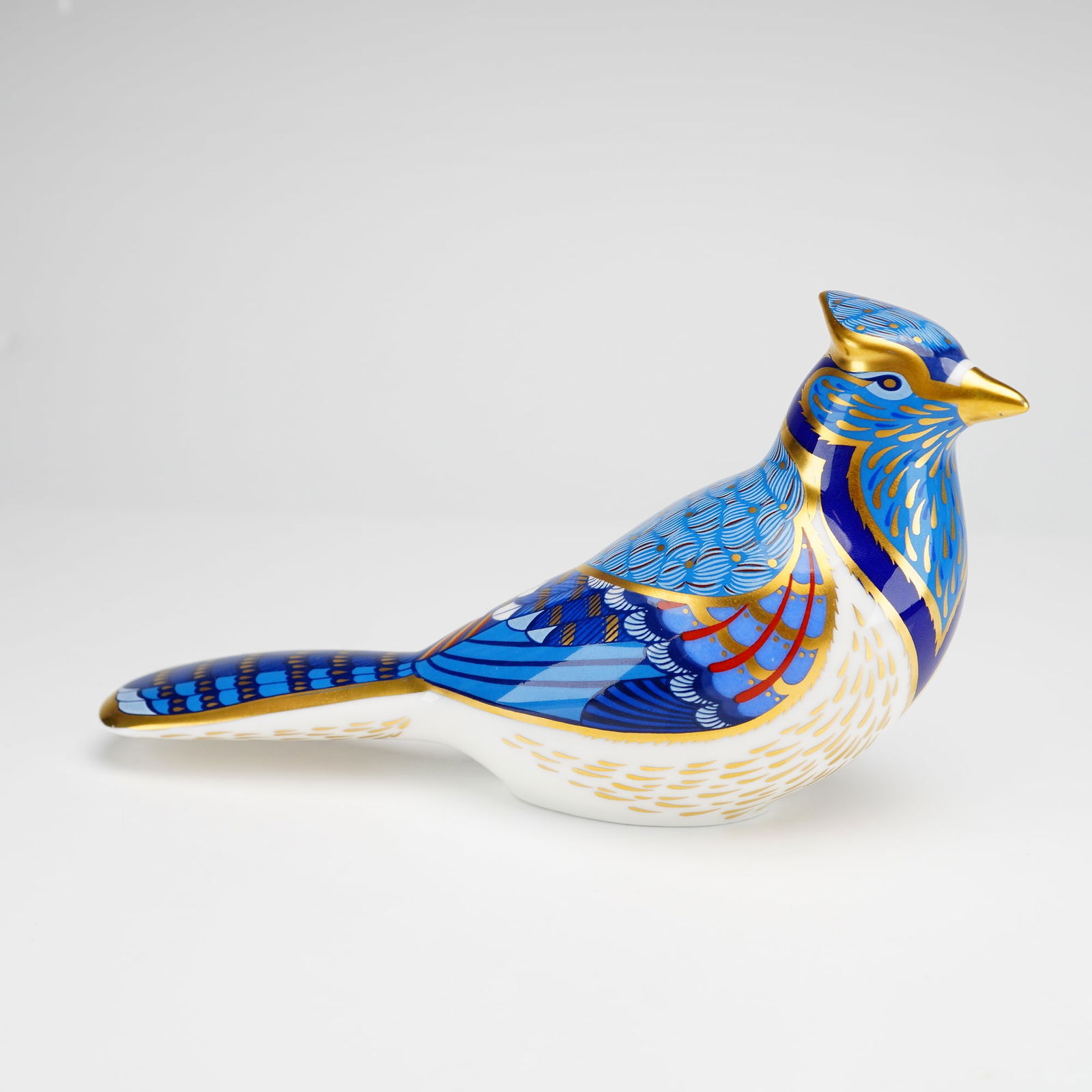Royal Crown Derby Bone China Paperweight, Blue Jay: The figurine is decorated in the Imari style with a palette of cobalt and light blue, accented with red and extensive gold gilding. The underside bears the red Royal Crown Derby factory mark. The base