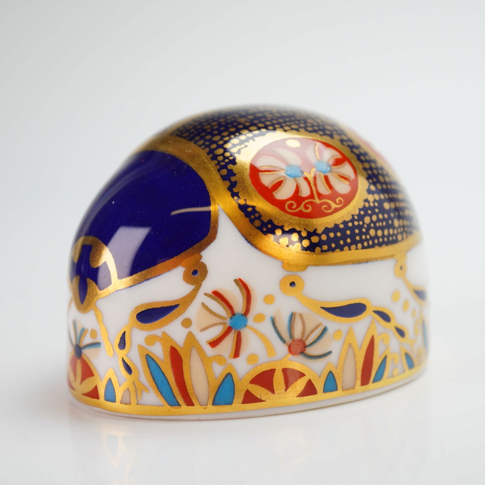 Royal Crown Derby Paperweight, Ladybird Blu: The piece is decorated in a traditional Imari pattern featuring cobalt blue, iron red, and 22ct gold gilding. The domed surface is ornamented with floral and foliate motifs. The underside bears the re