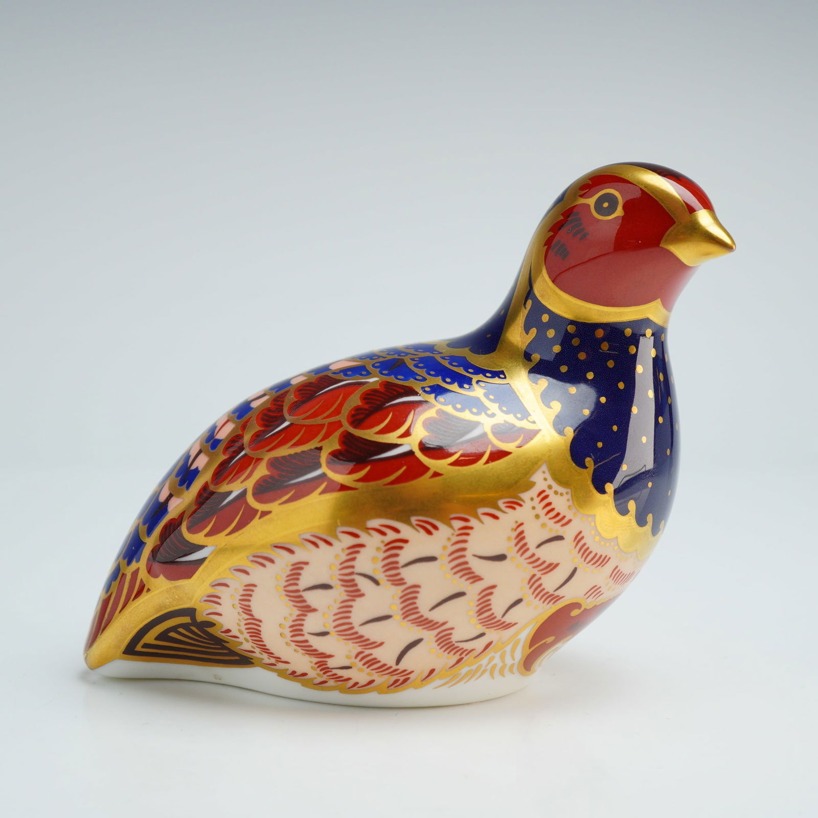 Royal Crown Derby Paperweight, Partridge: The piece is decorated in an Imari-style pattern featuring cobalt blue, iron red, and cream tones with 22kt gold gilding. The underside is marked in red script as number 3918 of a limited edition of 4