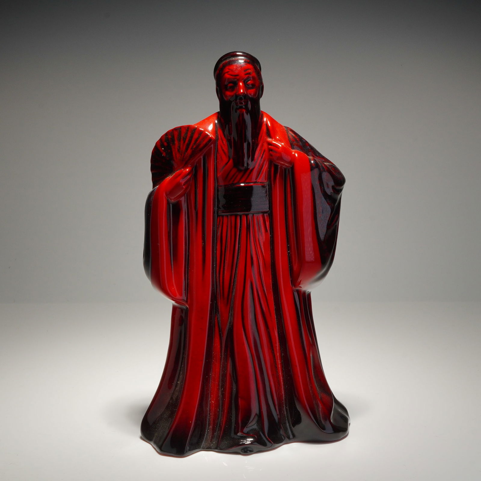 Royal Doulton Flambe Porcelain Confucius Figurine HN3314: This Royal Doulton Flambe porcelain figurine, titled Confucius and designated as model HN 3314, depicts the philosopher in traditional flowing robes while holding a fan. The piece is finished in the c