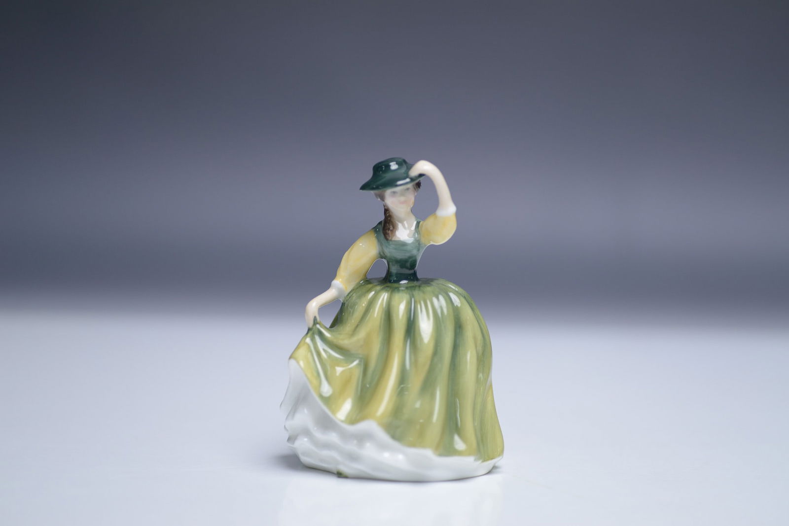 Royal Doulton Figurine, Buttercup HN3288: This Royal Doulton figurine, titled "Buttercup" (HN3288), was designed by Peggy Davies and measures 4"H. Crafted in fine china, it features a young woman in a green and yellow dress with delicate deta