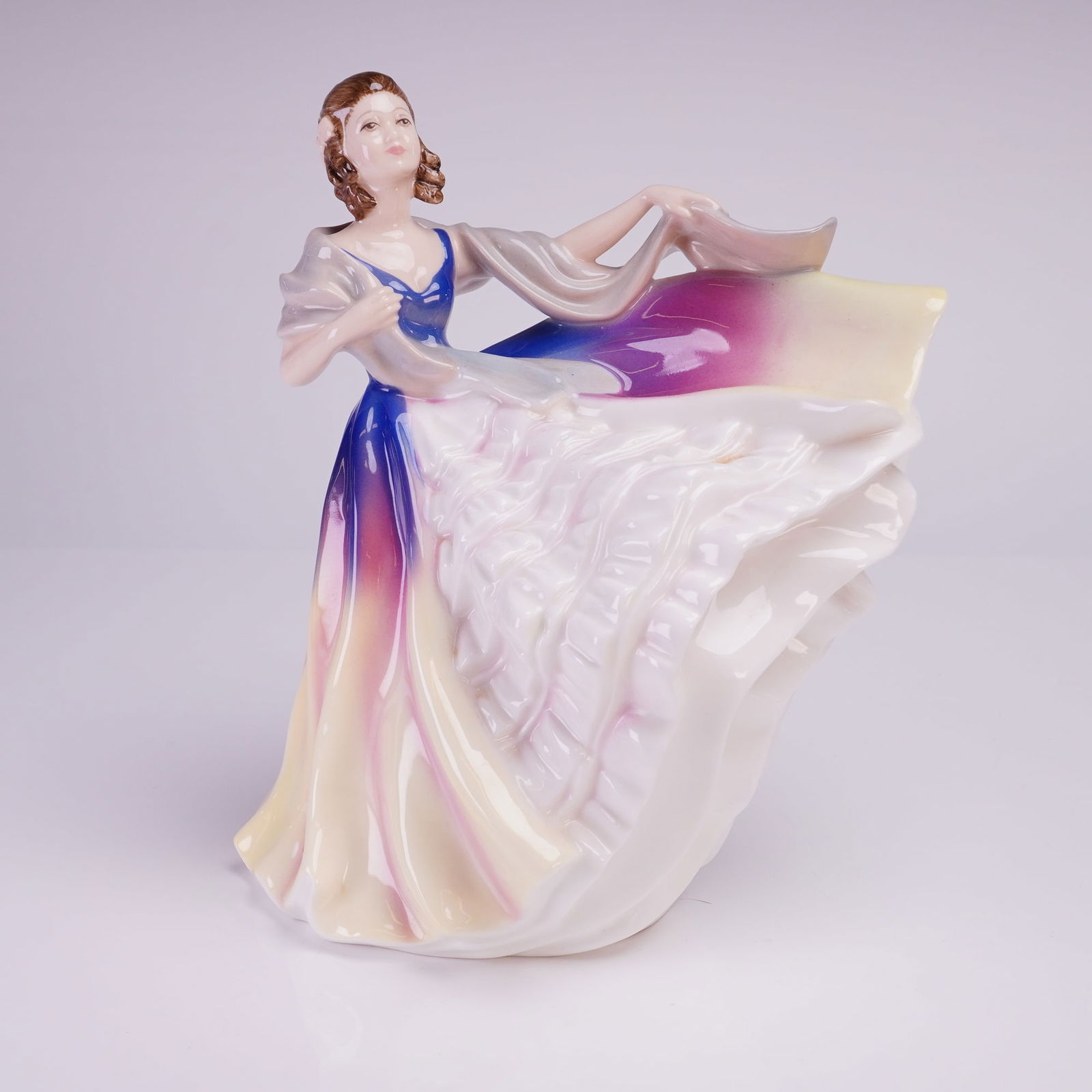 Royal Doulton Figurine, Lauren HN3290: The figure is captured in a dramatic pose with a voluminous, swirling gown and shawl. The decoration features hand-painted color transitions, including deep blue, magenta, yellow, and white, finished